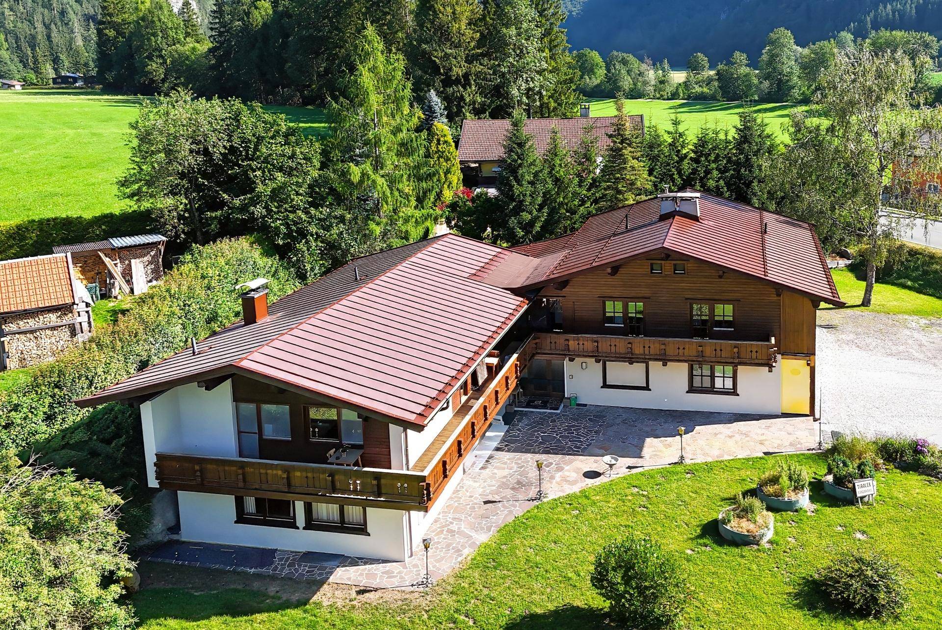 Luftaufnahme eines traditionellen Hauses mit roten Dächern und weitläufiger grüner Umgebung.