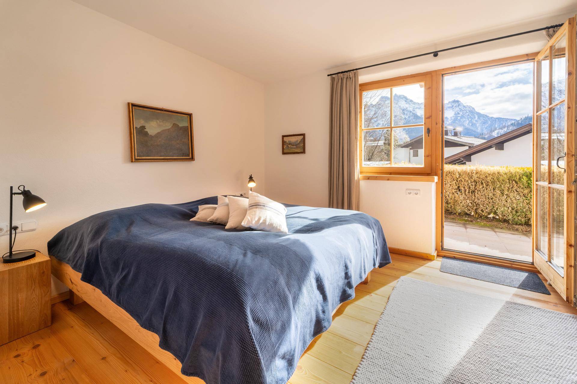 Helles Schlafzimmer mit Holzboden, direktem Zugang zum Außenbereich und Bergblick.