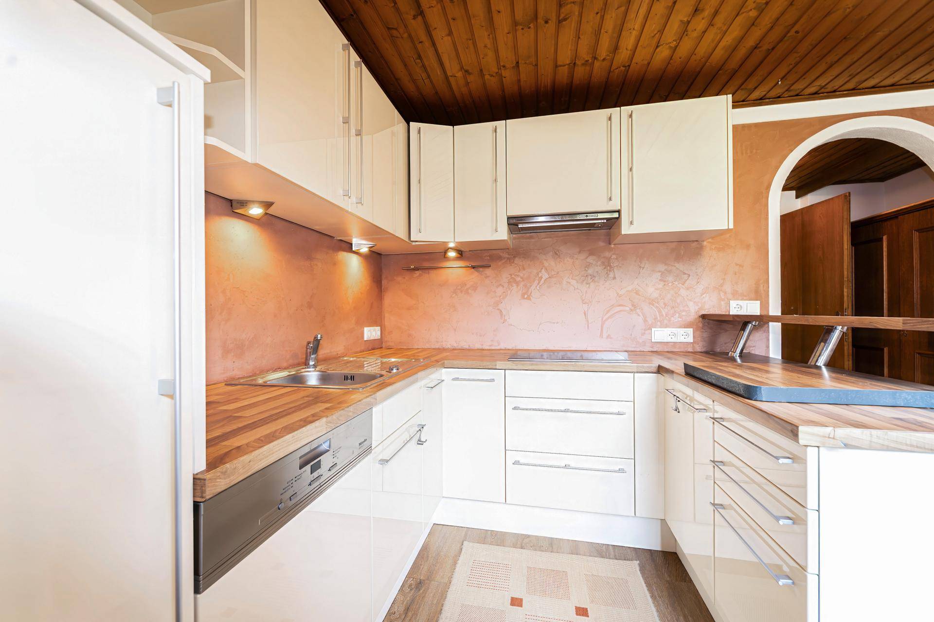 Funktionale Küche mit Spülmaschine, Kochfeld und Holzdecke, ideal für den täglichen Gebrauch.