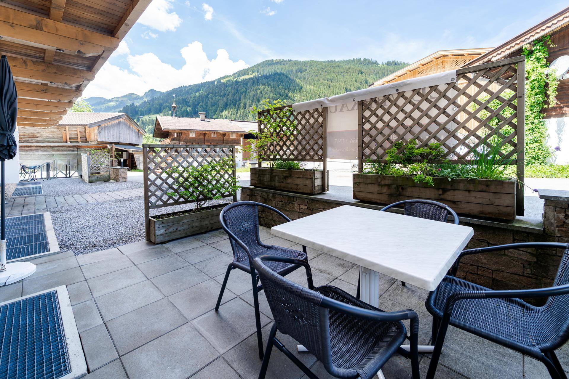 Gepflasterte Terrasse mit Sitzgelegenheiten und Blick auf die umliegende Berglandschaft.