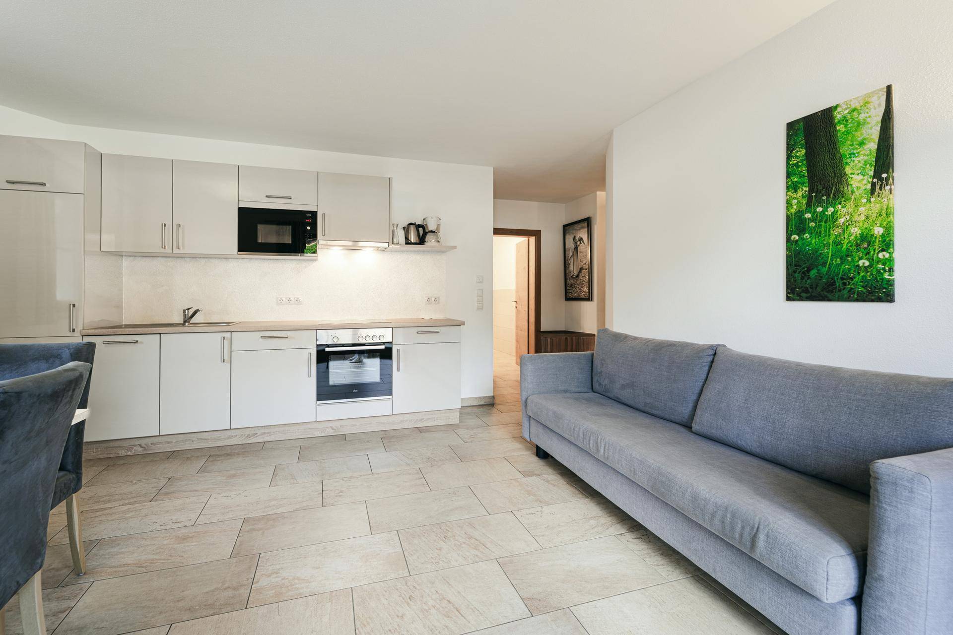 Moderne Küchenzeile mit integrierten Geräten und angrenzendem Wohnbereich mit Sofa.
