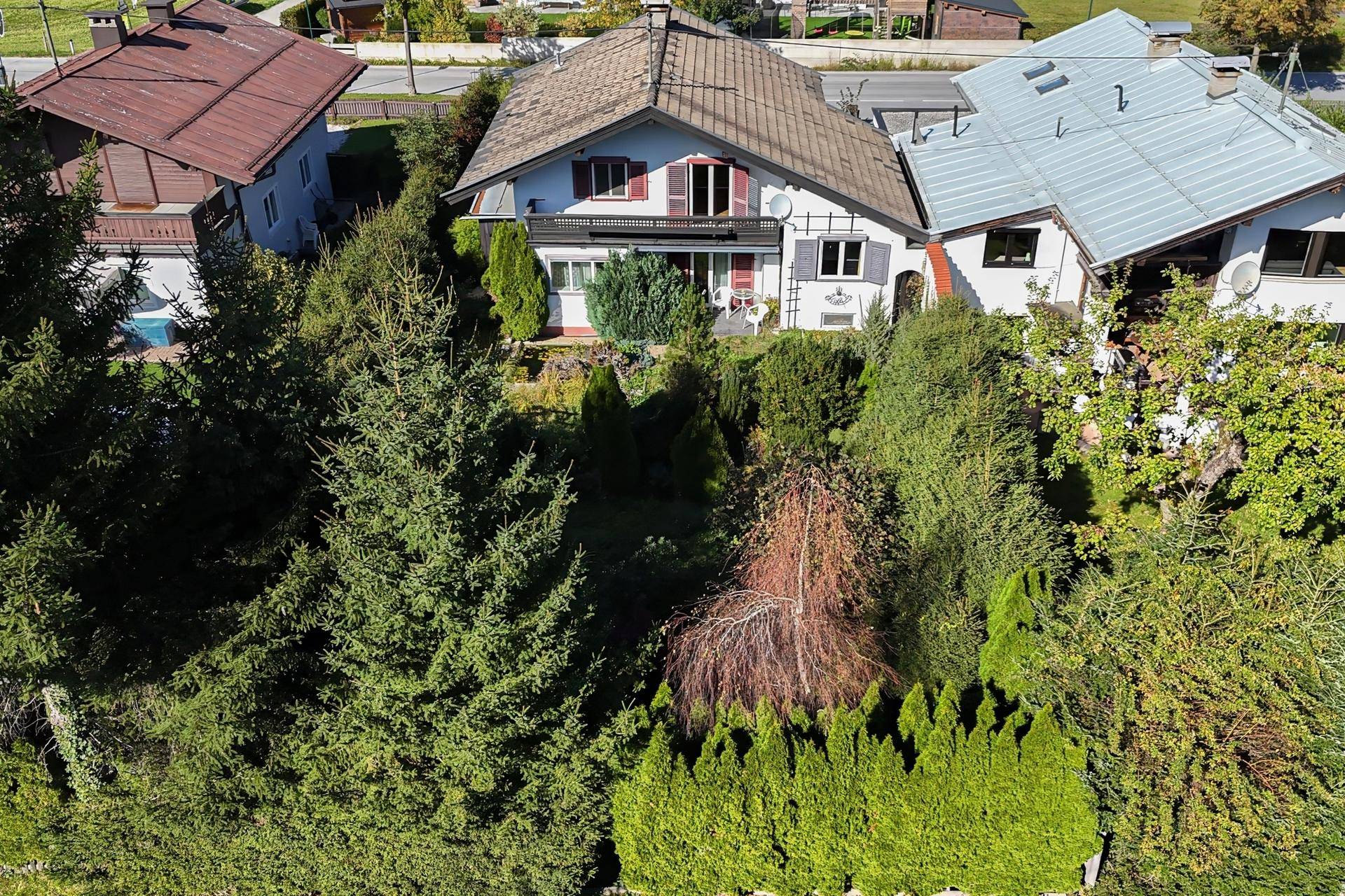 Vogelperspektive eines gepflegten Hauses mit üppigem Garten und vielen Bäumen.