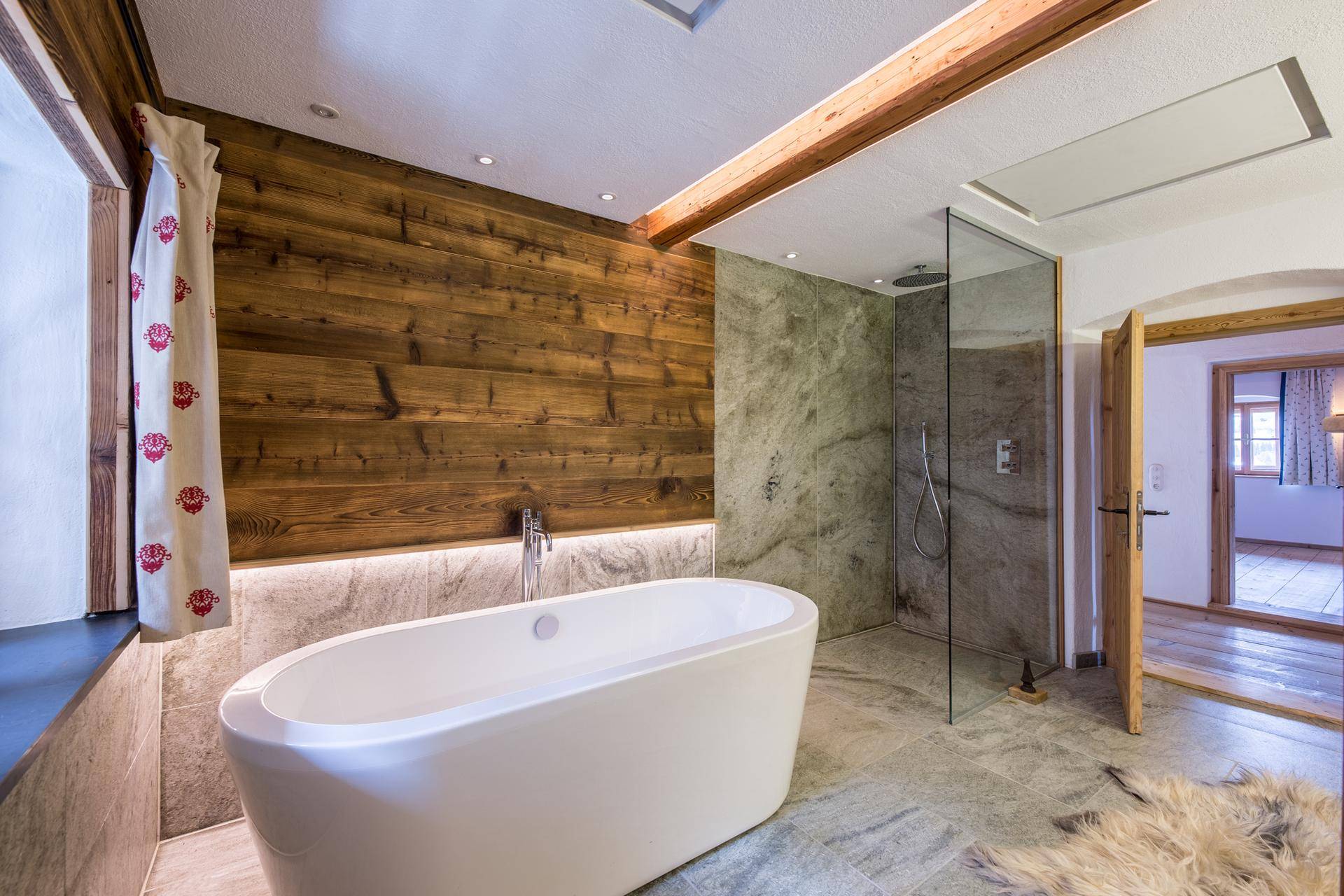 Elegantes Badezimmer mit freistehender Badewanne, begehbarer Dusche und Holzverkleidung.