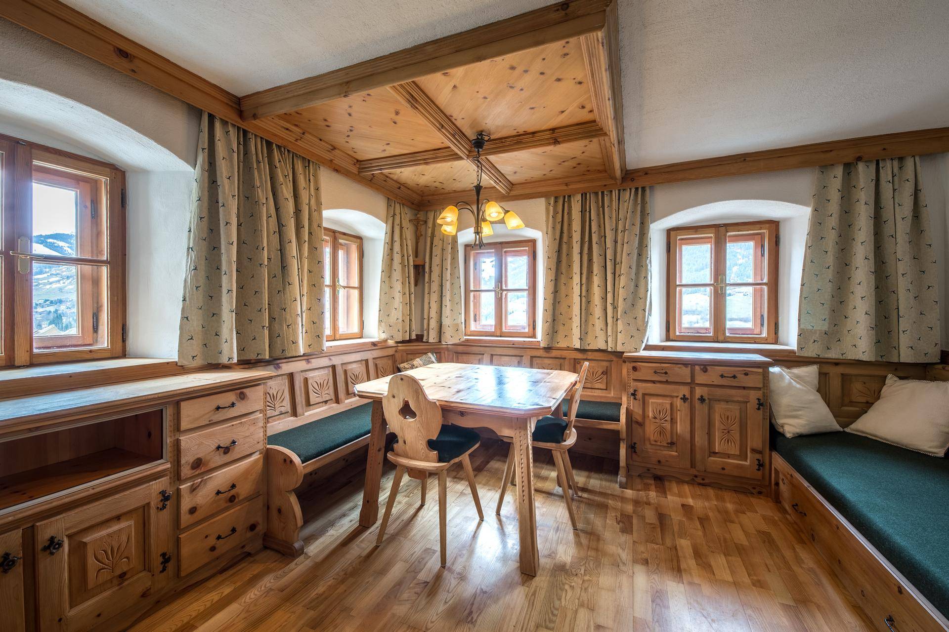Gemütlicher Essbereich im traditionellen Alpenstil mit Holztäfelung, Eckbank und Bergblick.