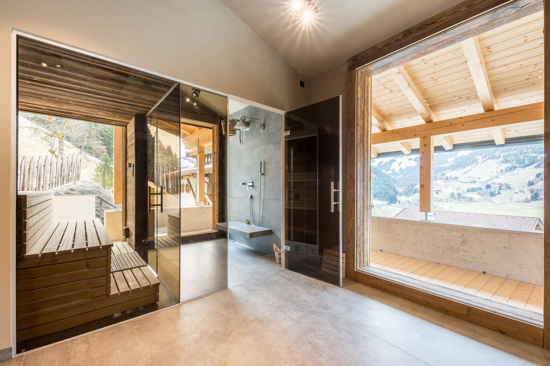 Moderner Wellnessbereich mit Sauna, Dusche und Panoramablick auf die Berge.