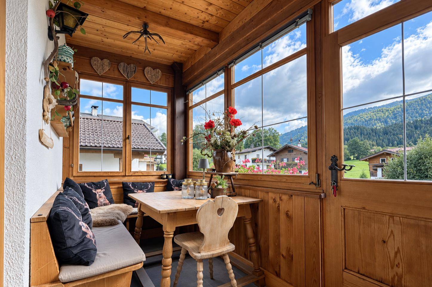 Gemütlicher Wintergarten mit Holztäfelung, Essbereich und Blick auf die Berge.