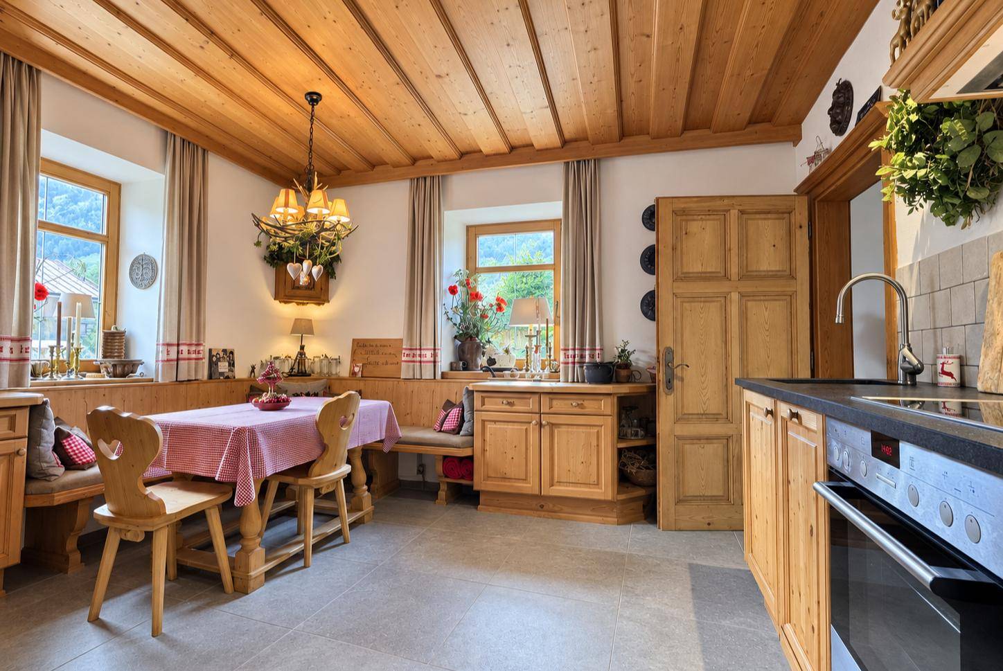 Traditionelle Wohnküche mit Holzeinbauten, Essbereich und modernen Geräten.