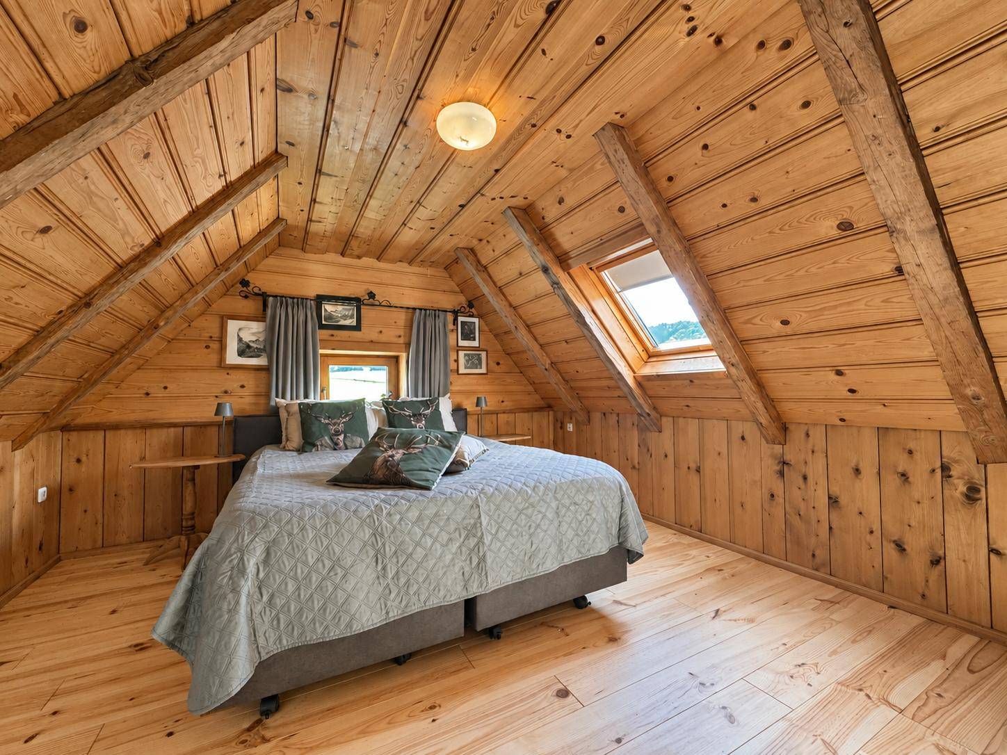 Dachgeschoss-Schlafzimmer mit Holzbalken, Dachschrägen und gemütlichem Doppelbett.