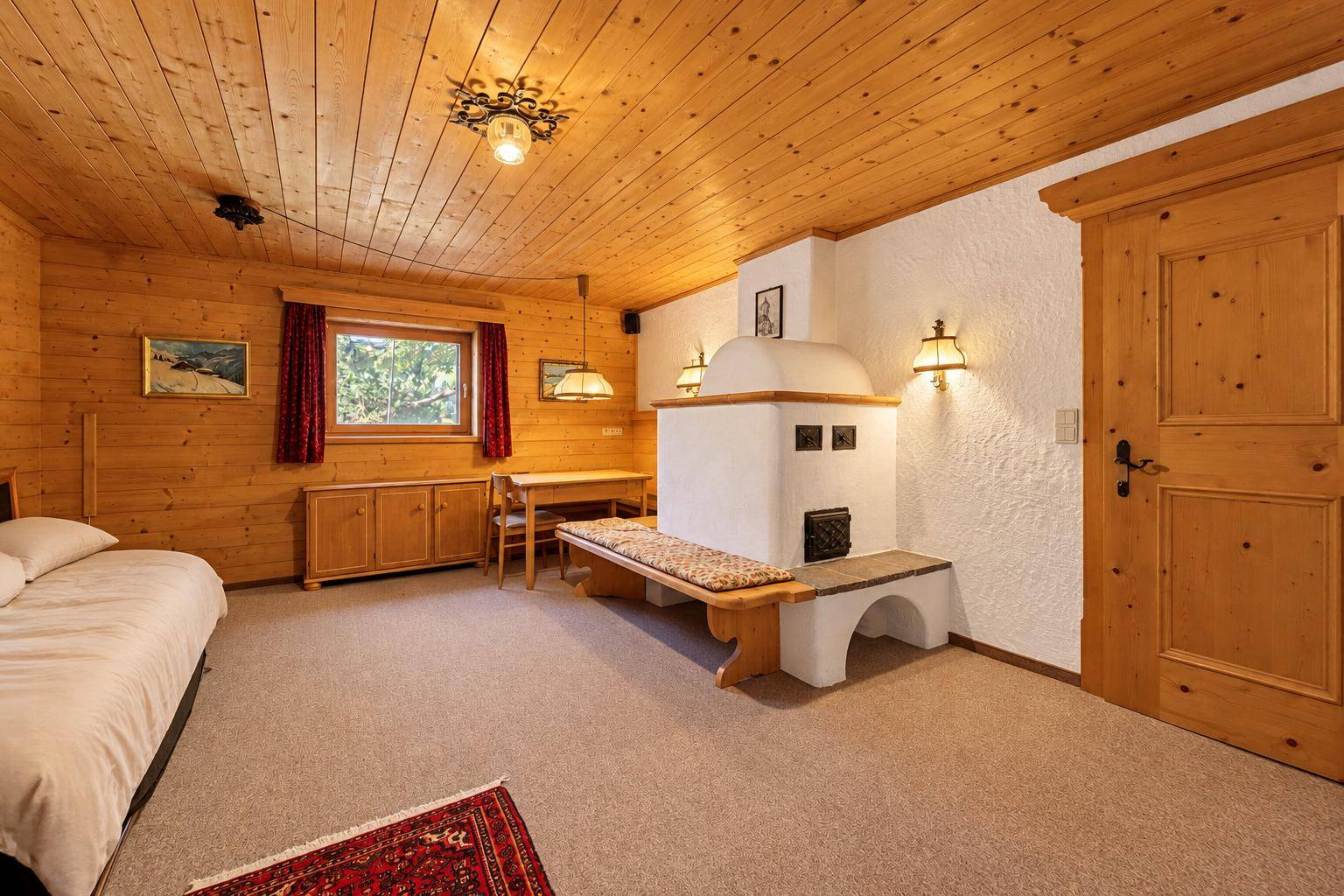Schlafzimmer im Landhausstil mit Holzwänden, Kachelofen und Teppichboden.