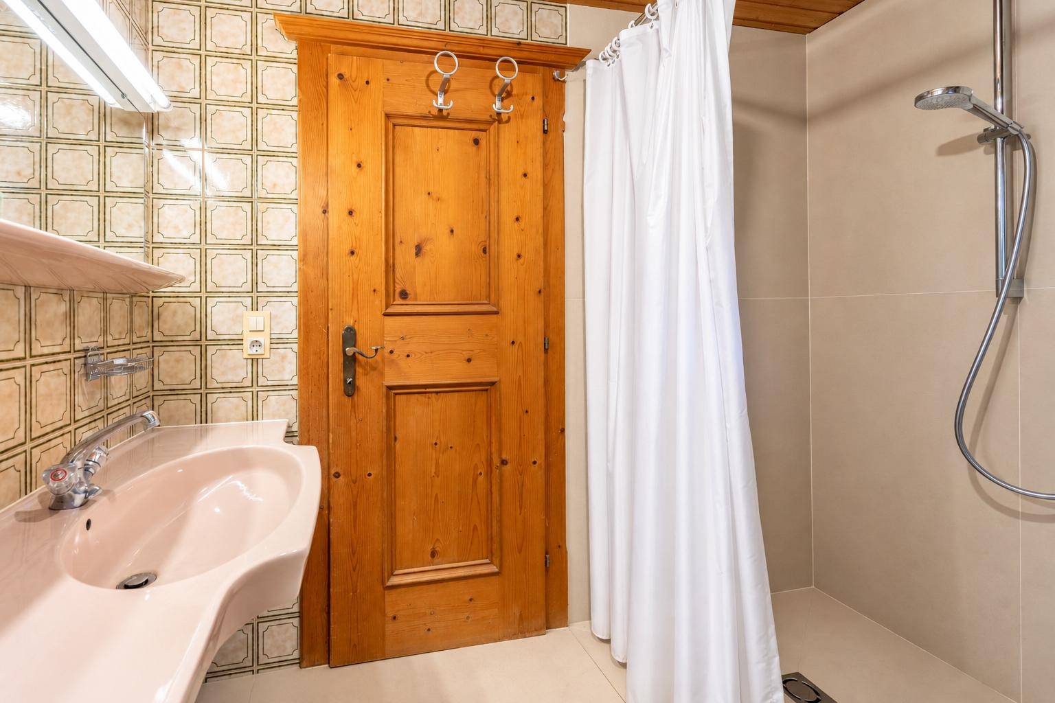 Badezimmer mit Duschkabine, Waschbecken und traditionellen Fliesen.