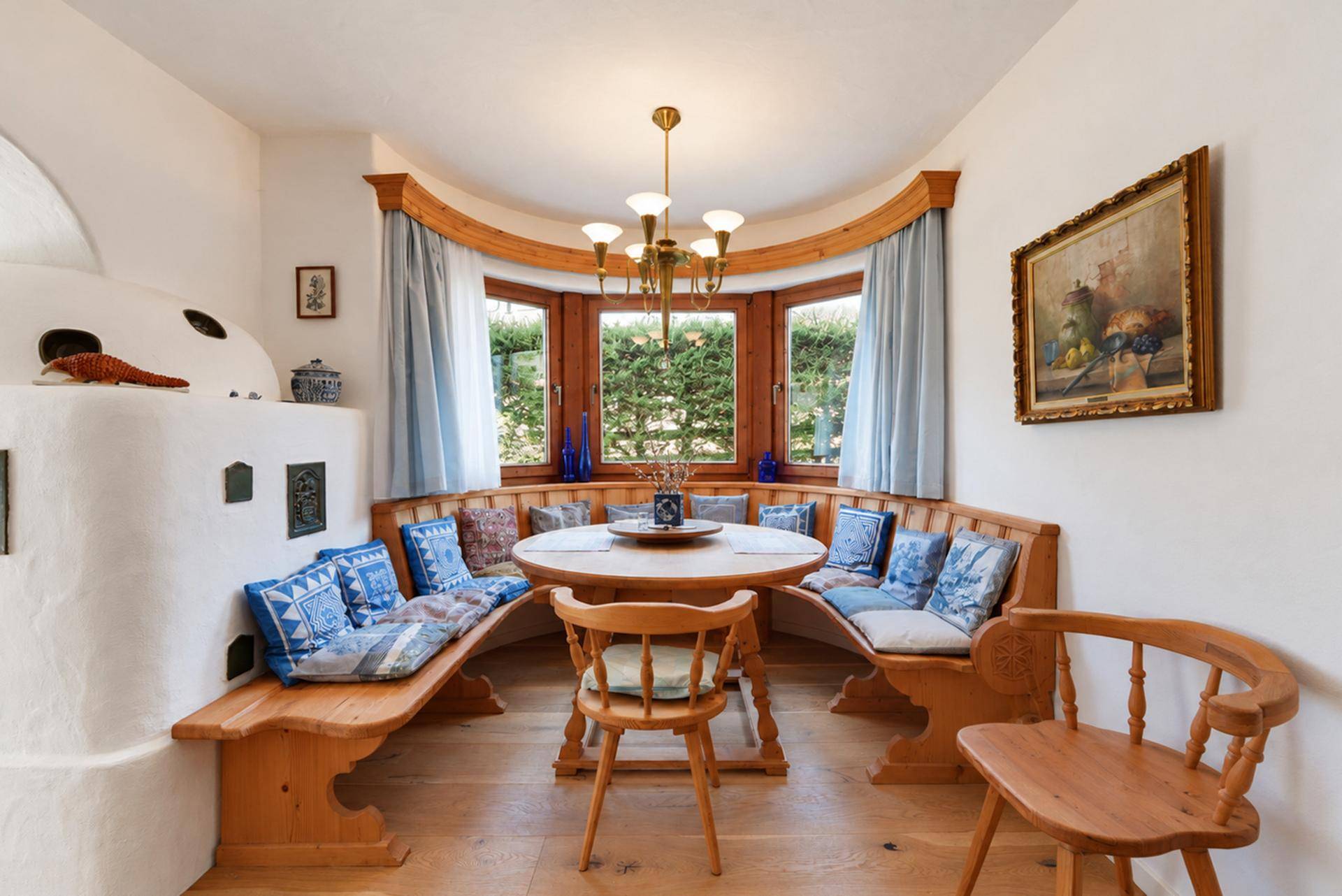 Traditioneller Essbereich mit Holzbänken, rundem Tisch und Blick in den grünen Garten.