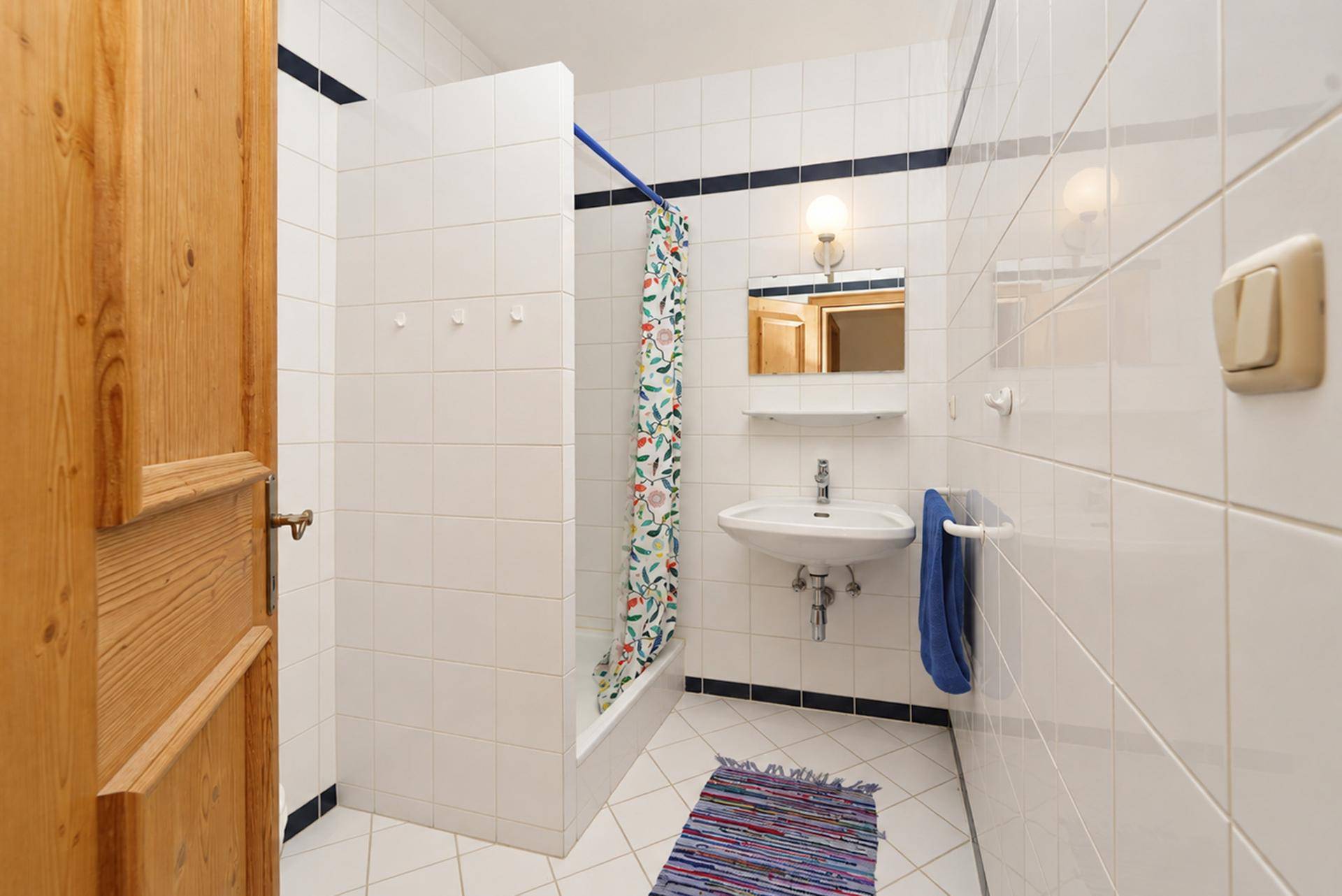 Kleines Badezimmer mit Dusche, Waschbecken und traditionellen Fliesen.
