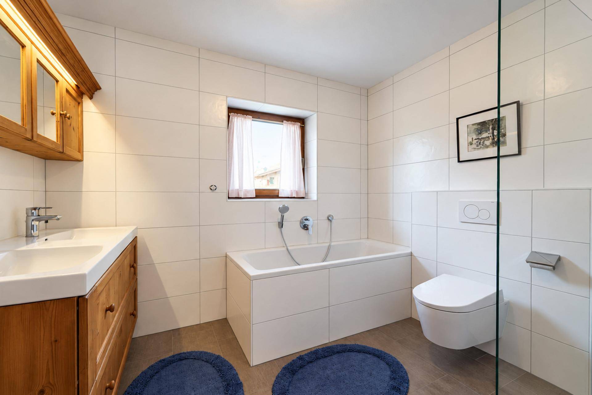 Modernisiertes Badezimmer mit Badewanne, Waschbecken, WC und Holzwaschtisch.