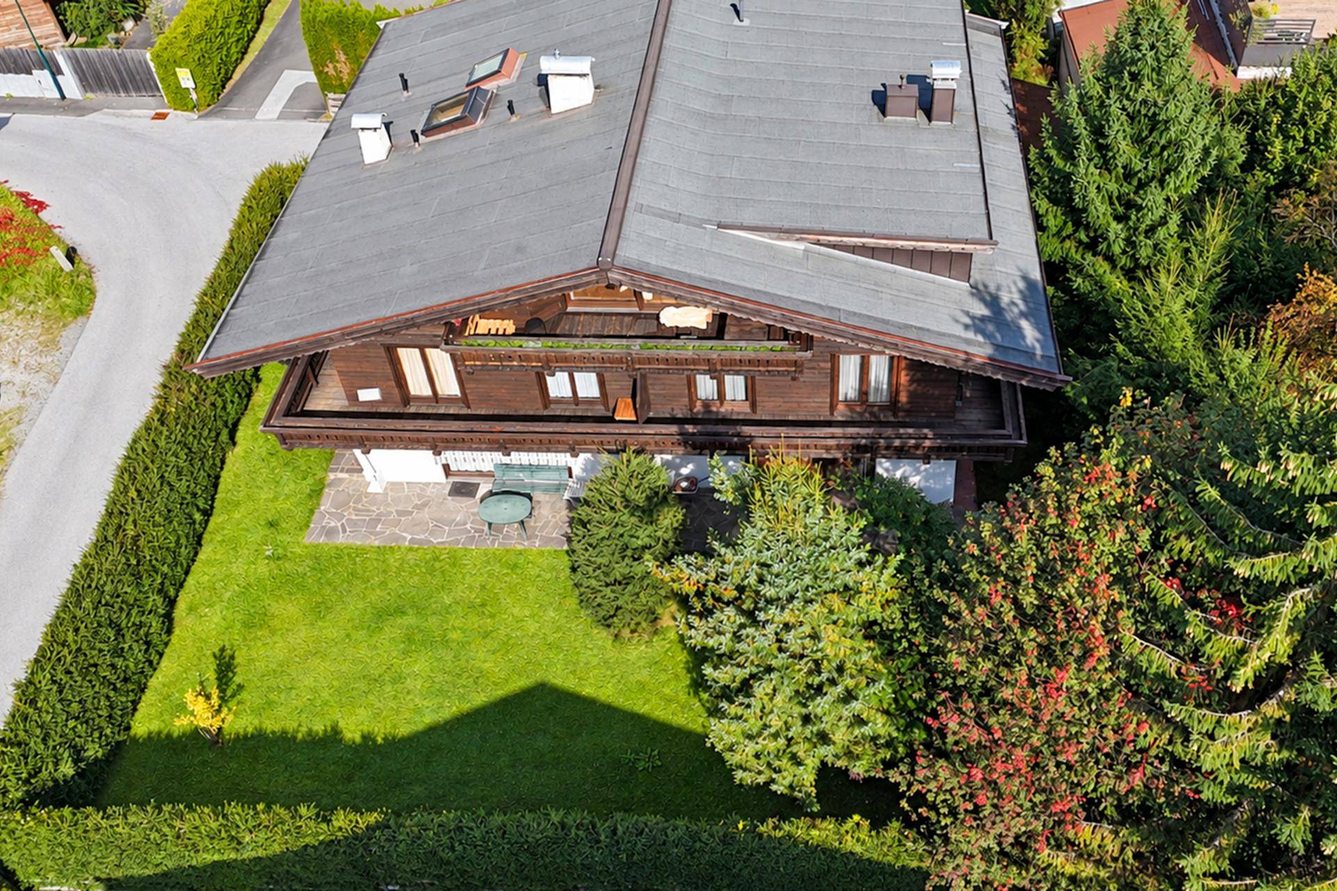 Luftaufnahme eines traditionellen Holzhauses mit Satteldach und umgebendem Garten.