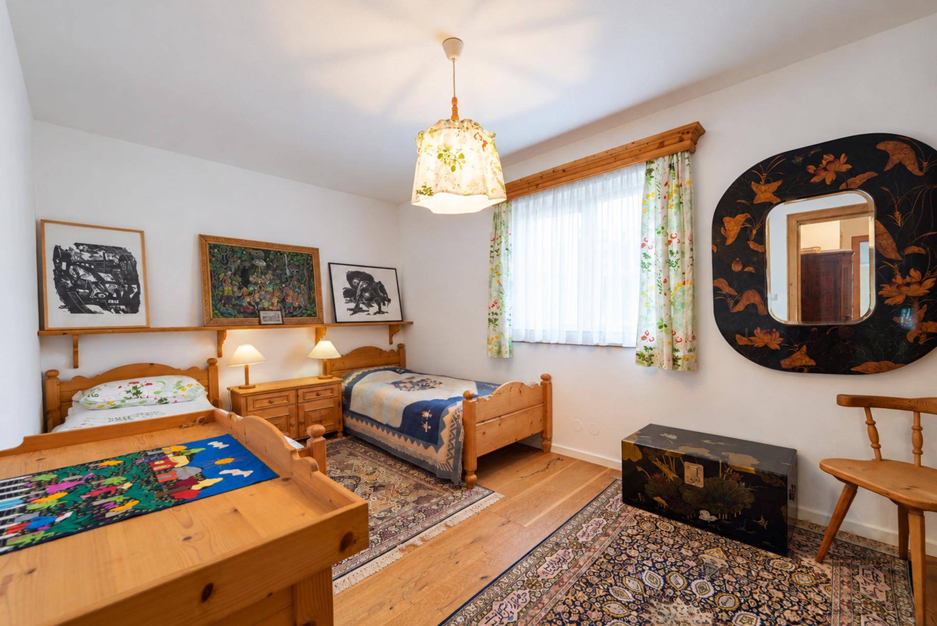 Kinderzimmer mit zwei Einzelbetten, Holzboden und traditionellen Teppichen.