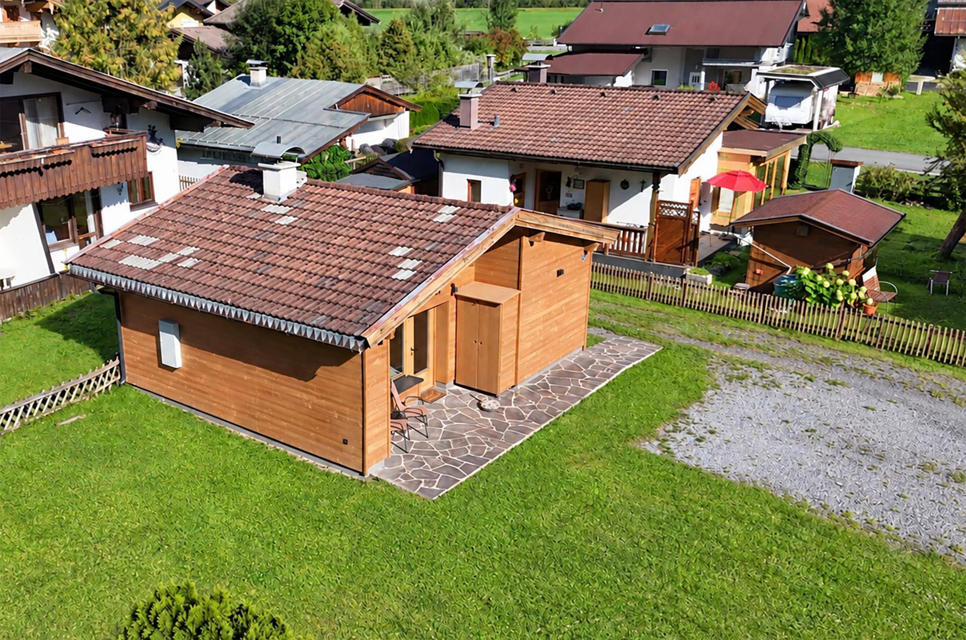 Luftaufnahme des Holzhauses mit Garten und der umliegenden ländlichen Bebauung.