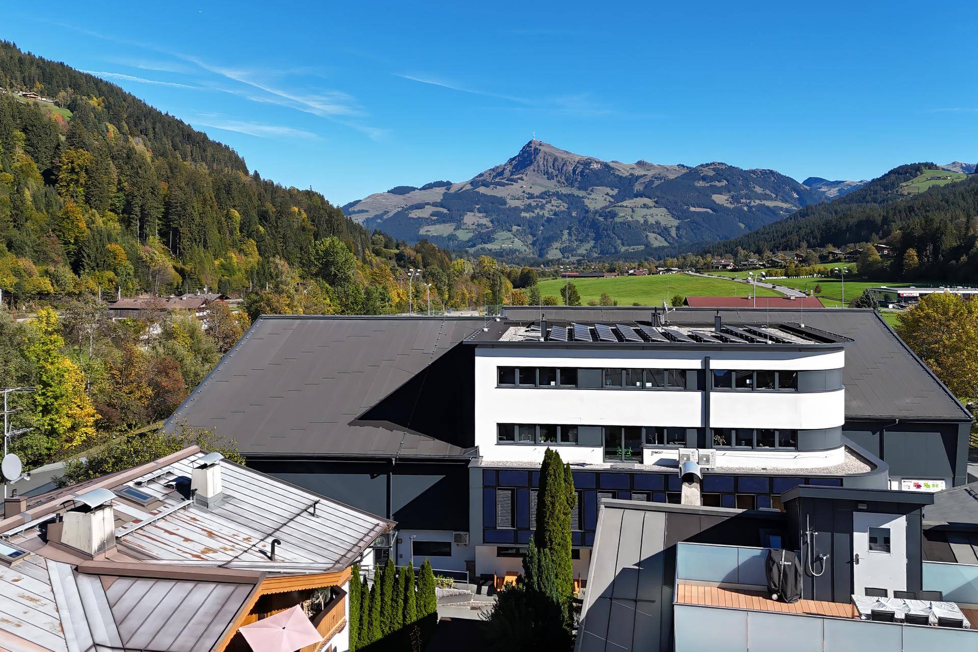 Weitläufiger Blick auf die Berglandschaft und ein modernes Gebäude mit Solaranlage auf dem Dach.