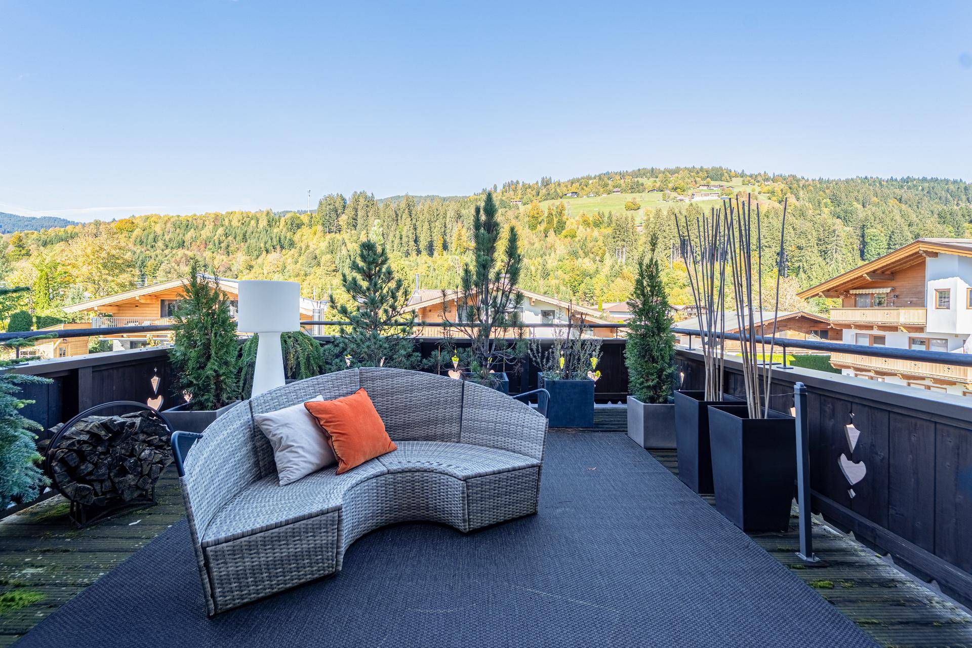 Große Dachterrasse mit bequemen Loungemöbeln und weitem Blick auf die grüne Hügellandschaft.