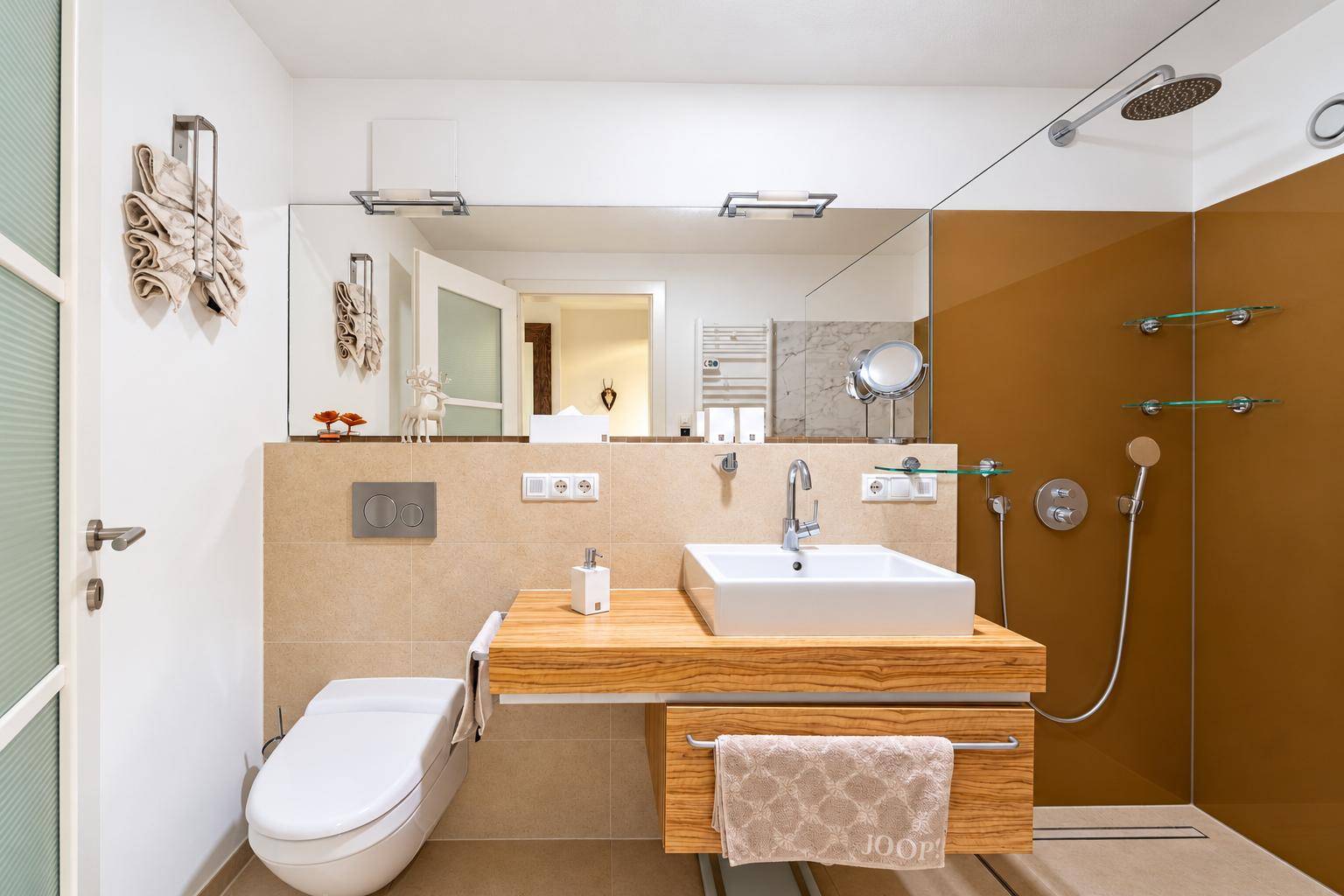 Modernes Badezimmer mit begehbarer Dusche, Holzwaschtisch und wandmontiertem WC in hellem Design.