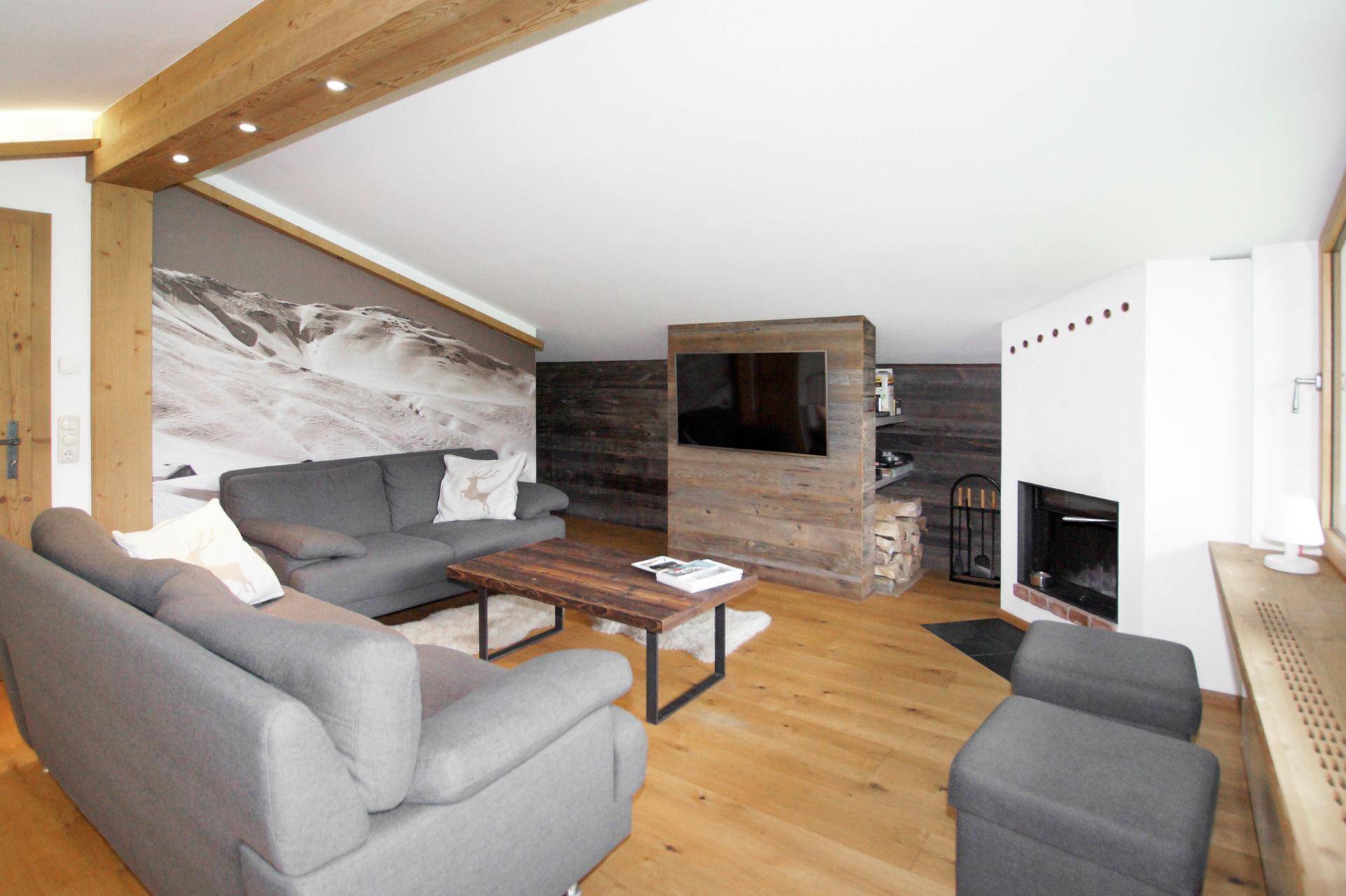 Gemütliches Wohnzimmer mit Kamin, Holzwänden und großem Sofa für entspannte Abende.