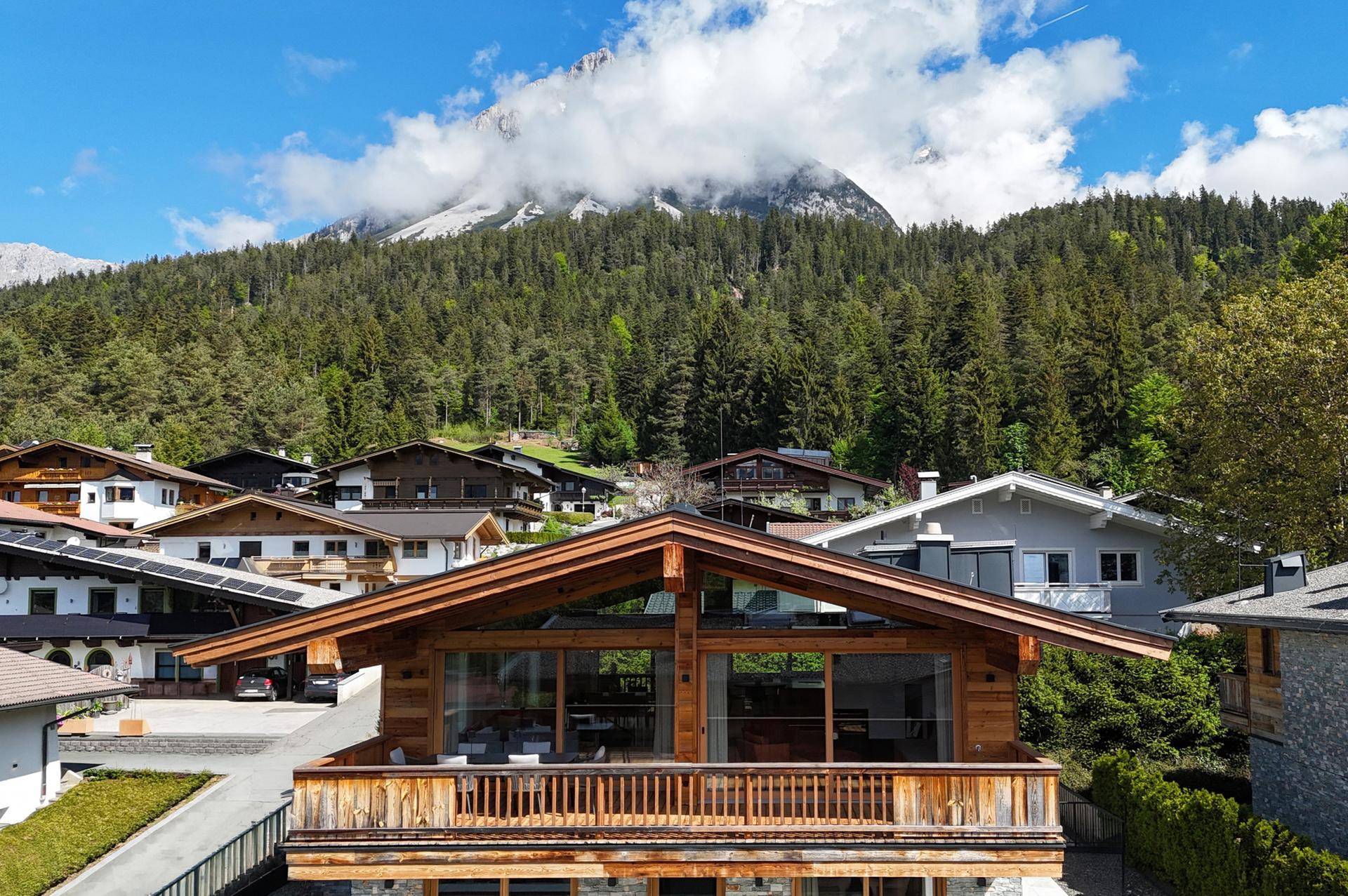 Exklusives Chalet mit traditioneller Holzverkleidung und großen Fenstern, umgeben von Natur und Bergen.