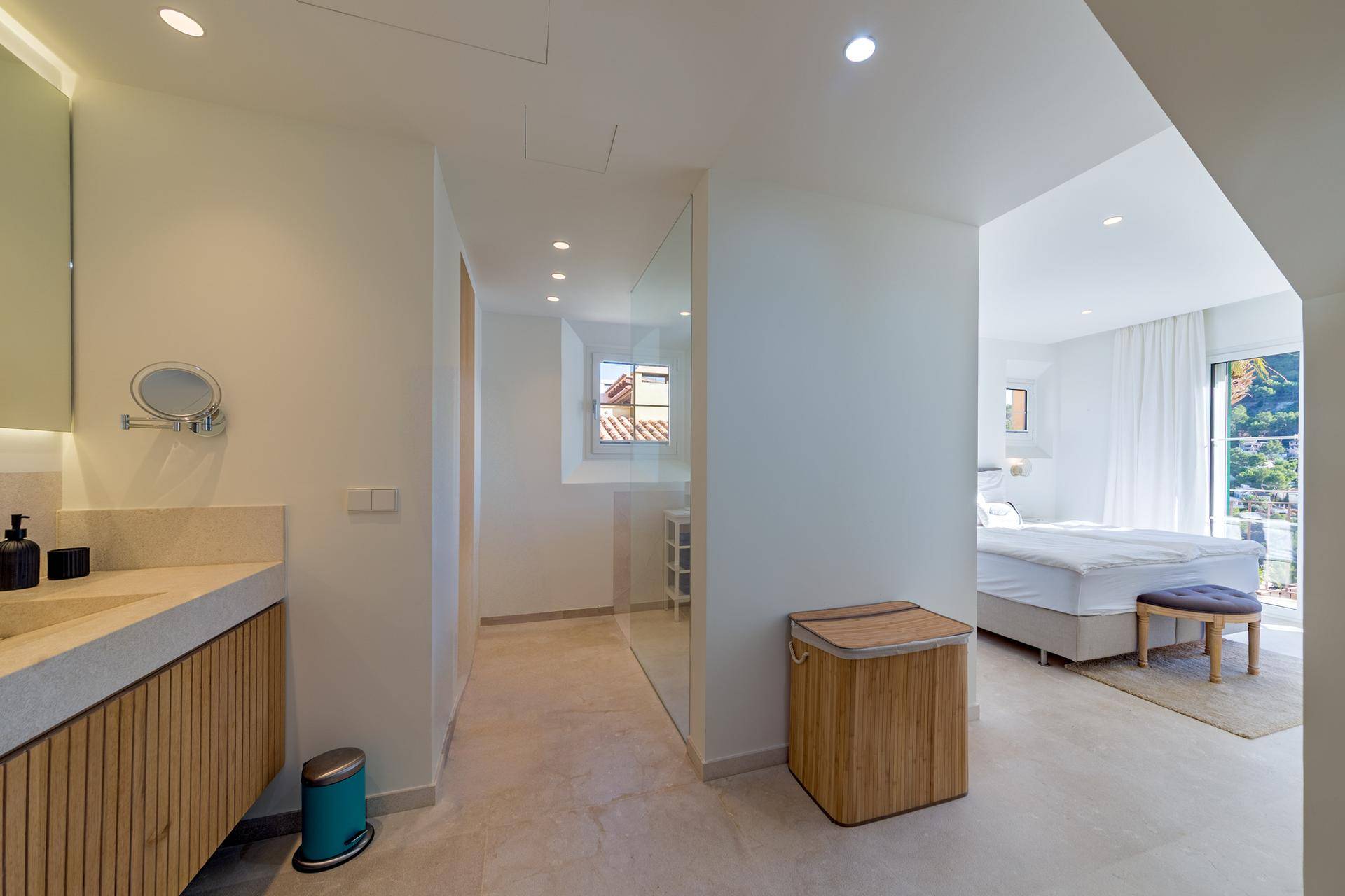 Modernes Badezimmer mit Doppelwaschbecken, begehbarer Dusche und direktem Zugang zum Schlafzimmer.