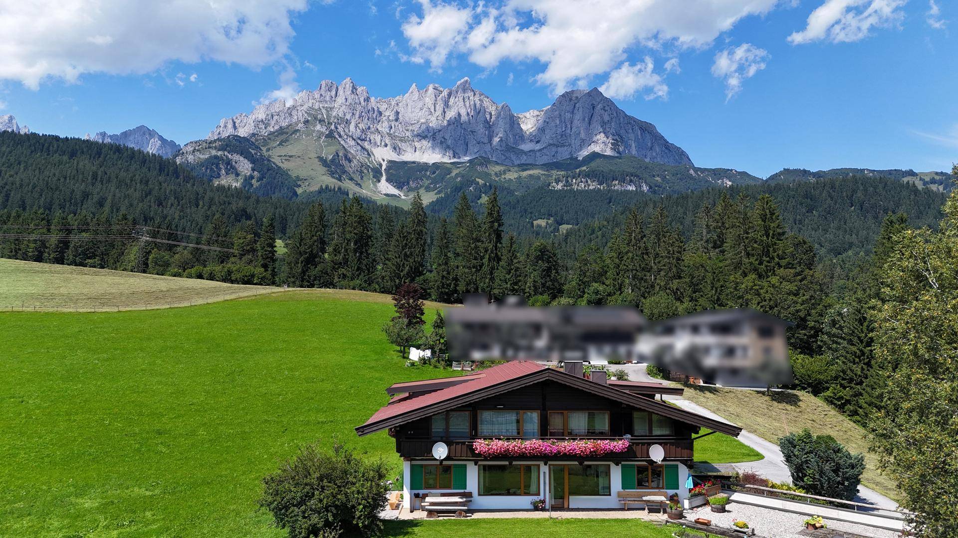 Traditionelles Haus in alpiner Landschaft mit beeindruckendem Bergpanorama und grünen Wiesen.