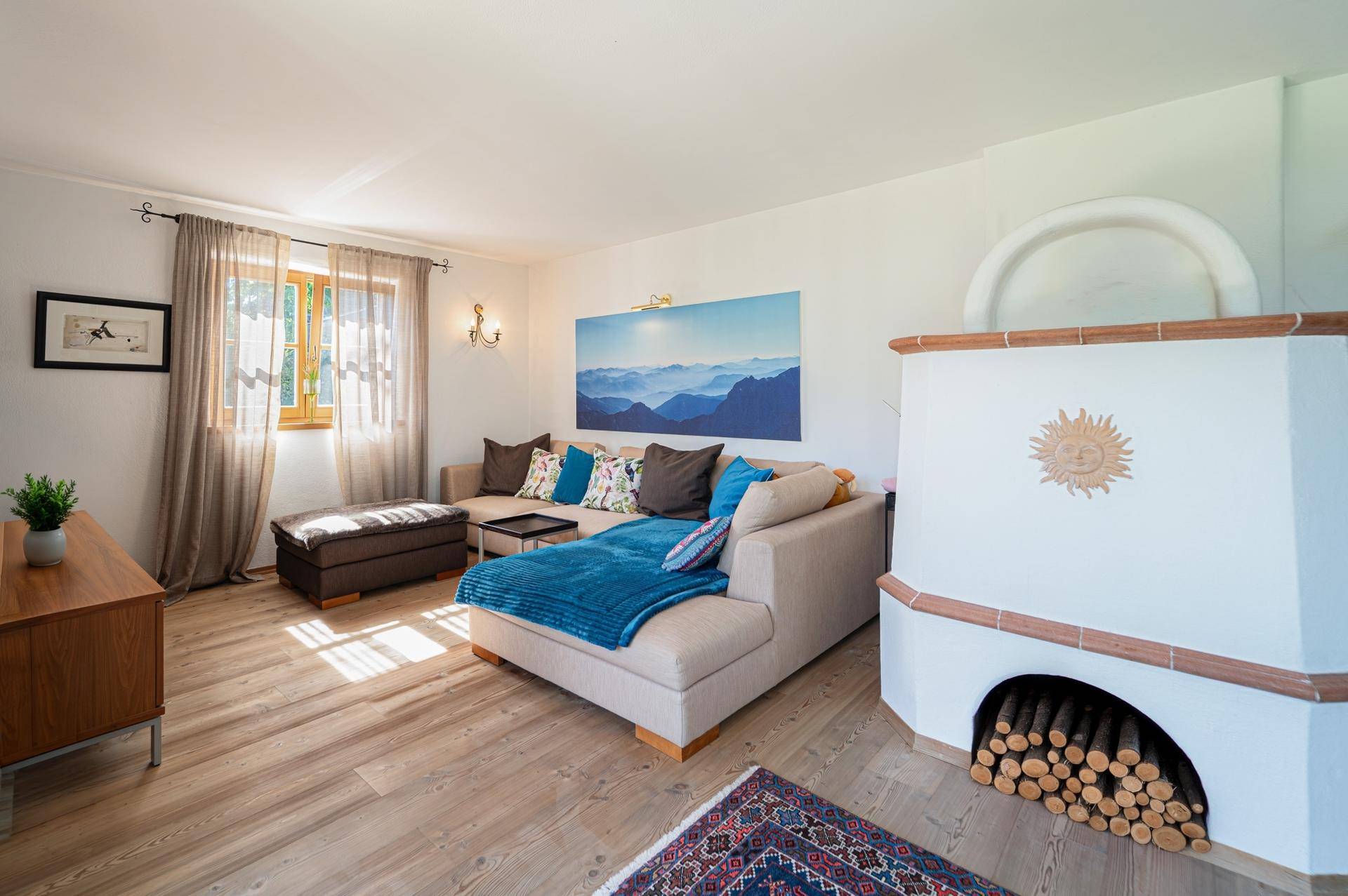 Gemütliches Wohnzimmer mit hellem Holzboden, beigem Sofa und einem traditionellen Kachelofen.