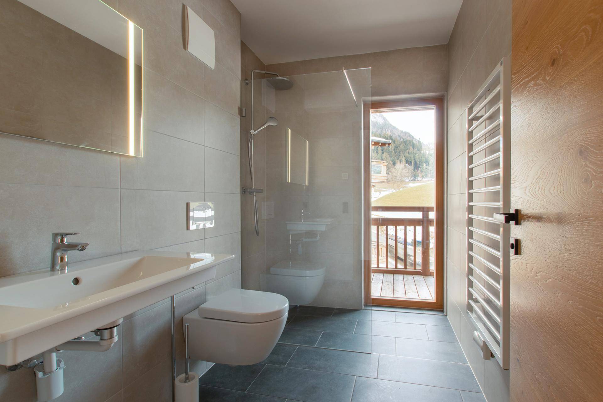 Modernes Badezimmer mit begehbarer Dusche, beheiztem Handtuchhalter und Balkonzugang.