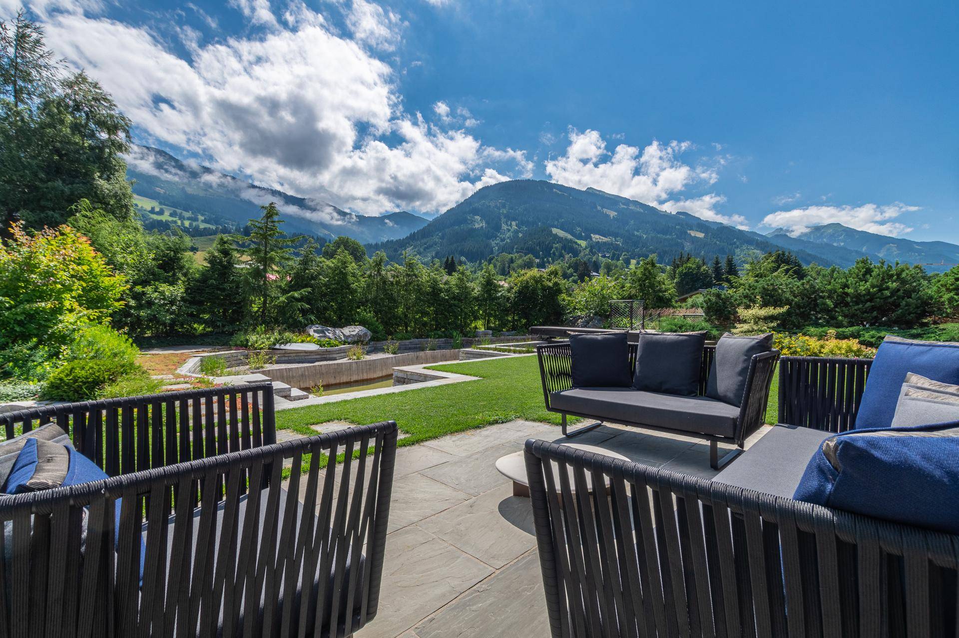 Große Terrasse mit modernen Gartenmöbeln und Panoramablick auf die Berge.