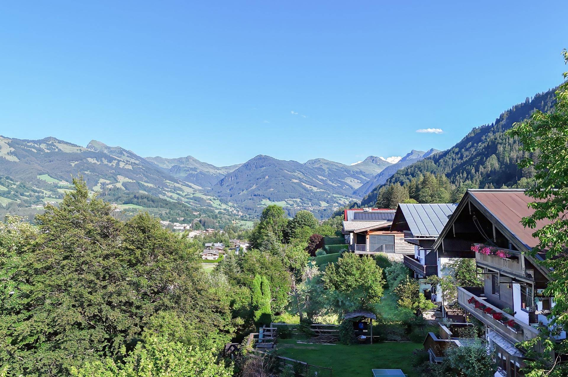 Panoramablick über ein grünes Tal mit verstreuten Häusern und Bergen am Horizont.