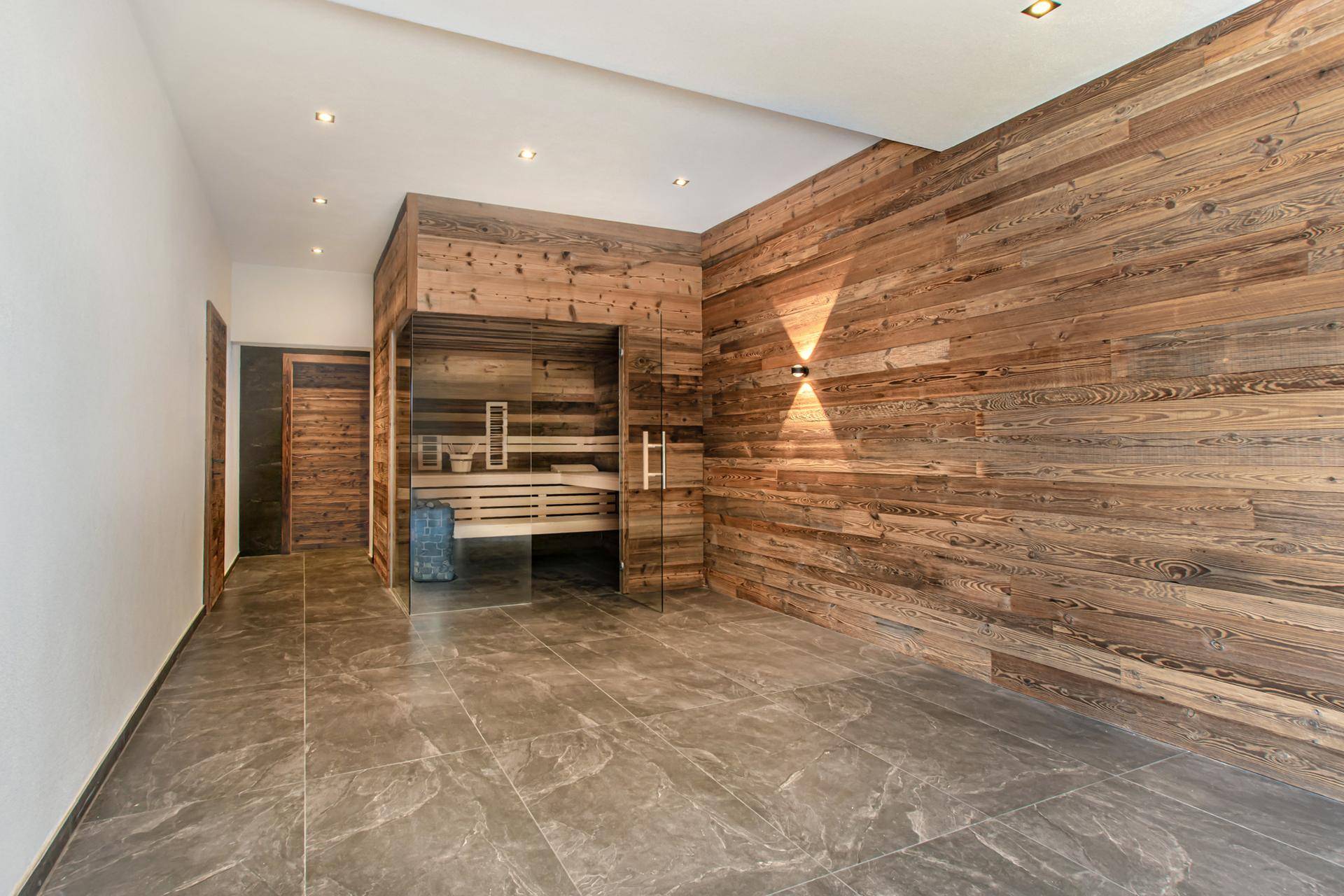 Geräumiger Wellnessbereich mit moderner Sauna und Holzverkleidung, ideal zur Entspannung.