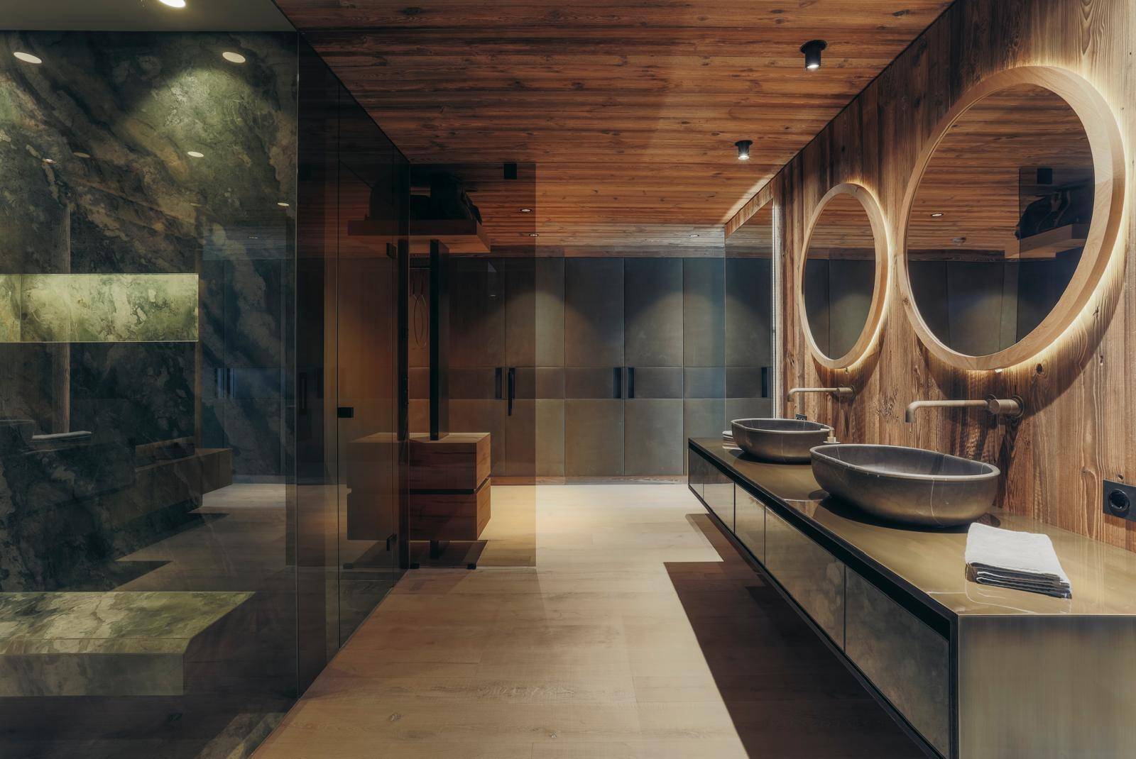 Luxuriöses Badezimmer mit Holzdecke, runden Spiegeln und eleganten Waschtischen.