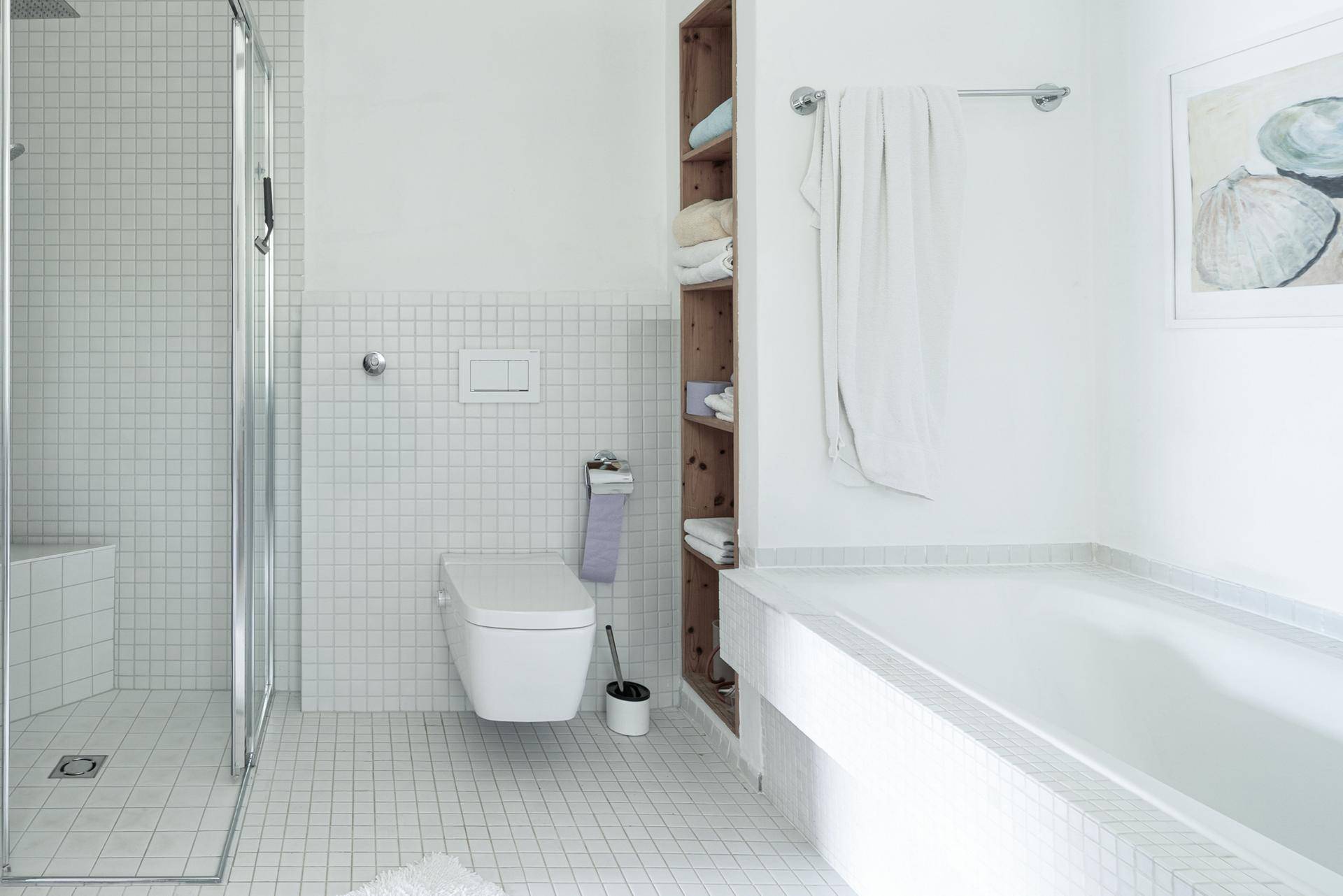 Modernes Badezimmer mit Badewanne, Dusche und Wand-WC, komplett gefliest in Weiß.