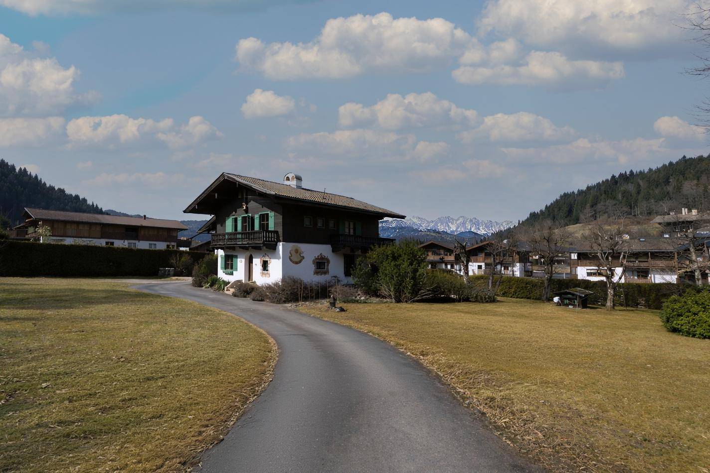 Alpenländisches Haus mit Zufahrt und weitem Blick auf die umliegende Berglandschaft.