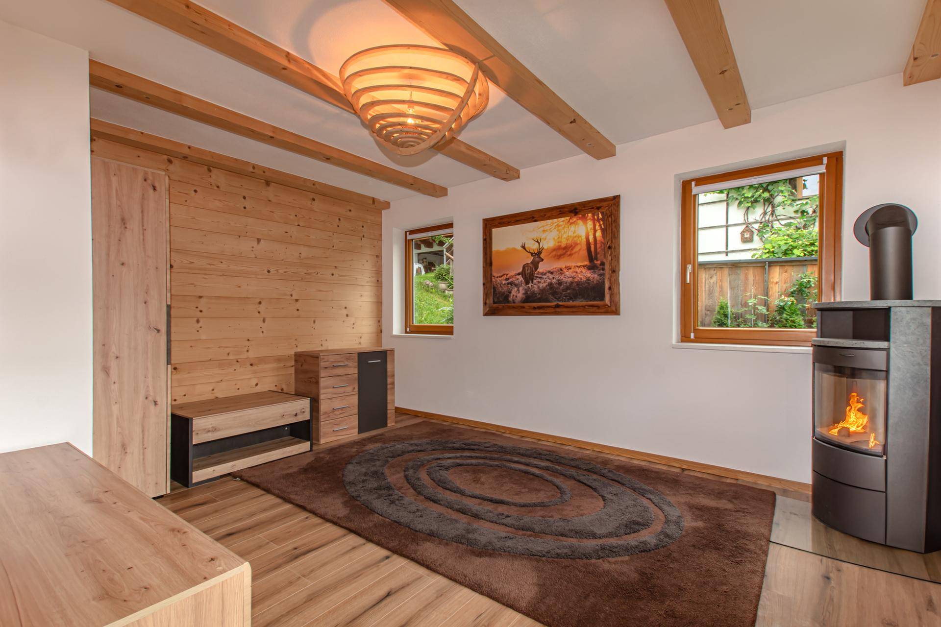 Gemütliches Schlafzimmer mit Holzbalken, Holzwänden, Kaminofen und Blick in den Garten.