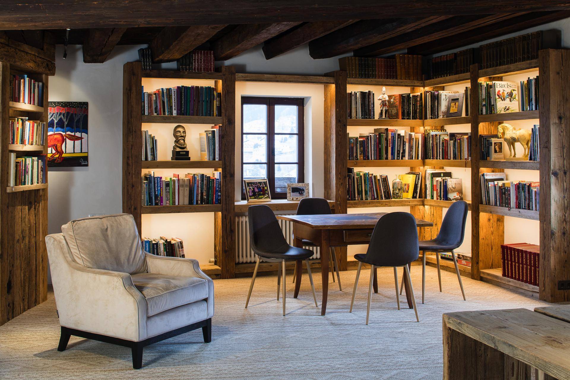 Elegante Bibliothek mit raumhohen Bücherregalen, Holzbalkendecke und Lesebereich.