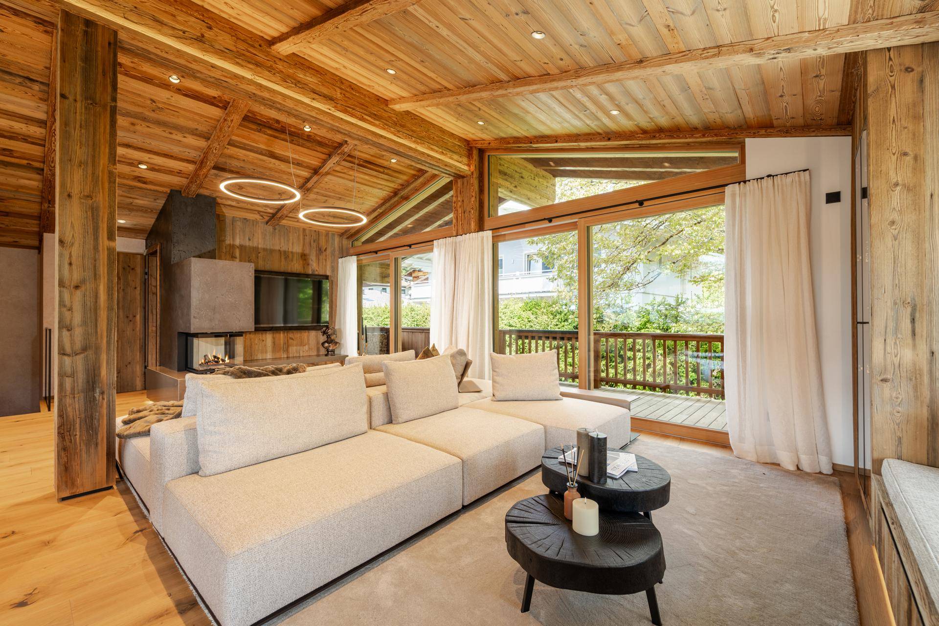 Heller Wohnbereich mit großem Ecksofa, modernen Couchtischen und Zugang zum Balkon durch Glasfront.
