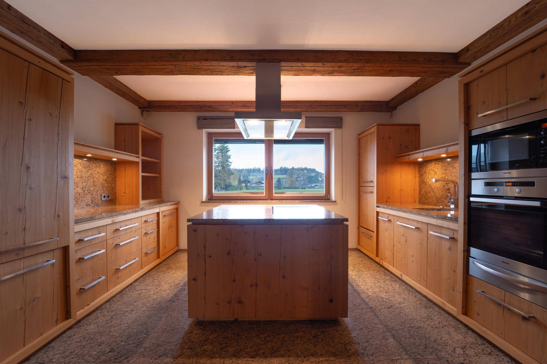 Geräumige Holzküche mit Kochinsel, Granitarbeitsplatten und Fenster mit Ausblick.