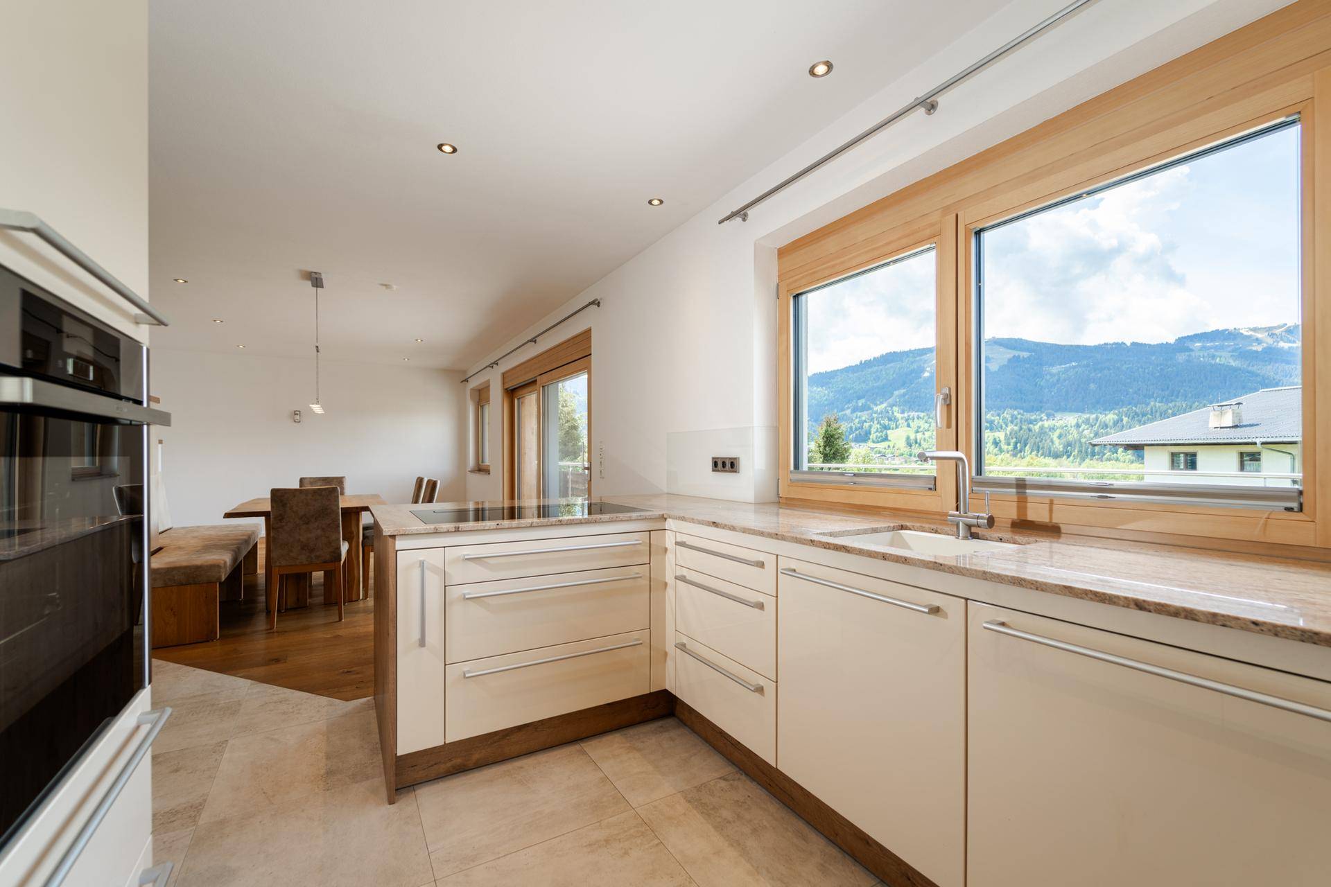 Helle Einbauküche mit modernen Geräten, Granitarbeitsplatte und Fenster mit Bergblick.