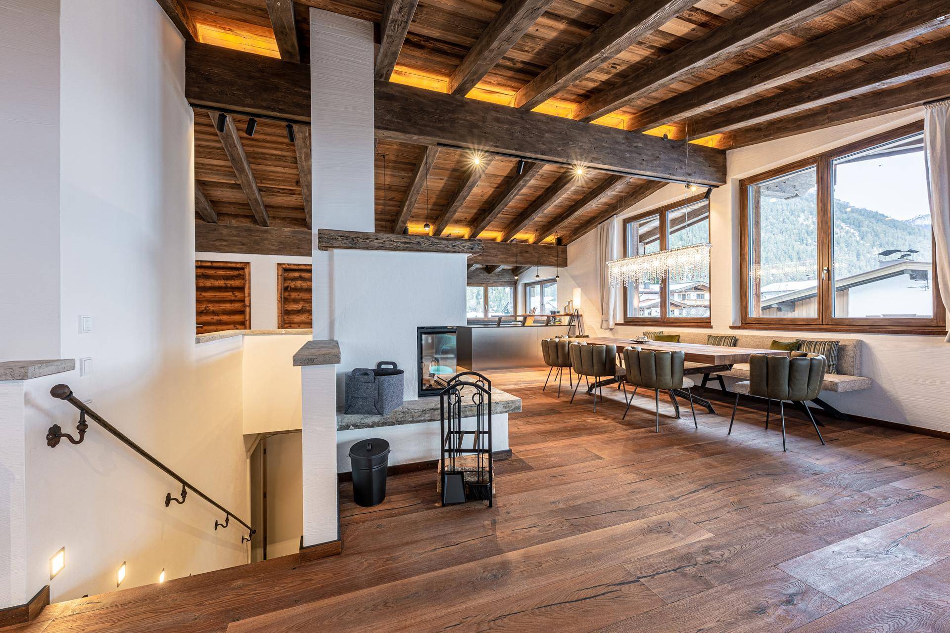 Offener Wohn-Essbereich mit Holzbalkendecke, Kamin und großzügigen Fenstern.