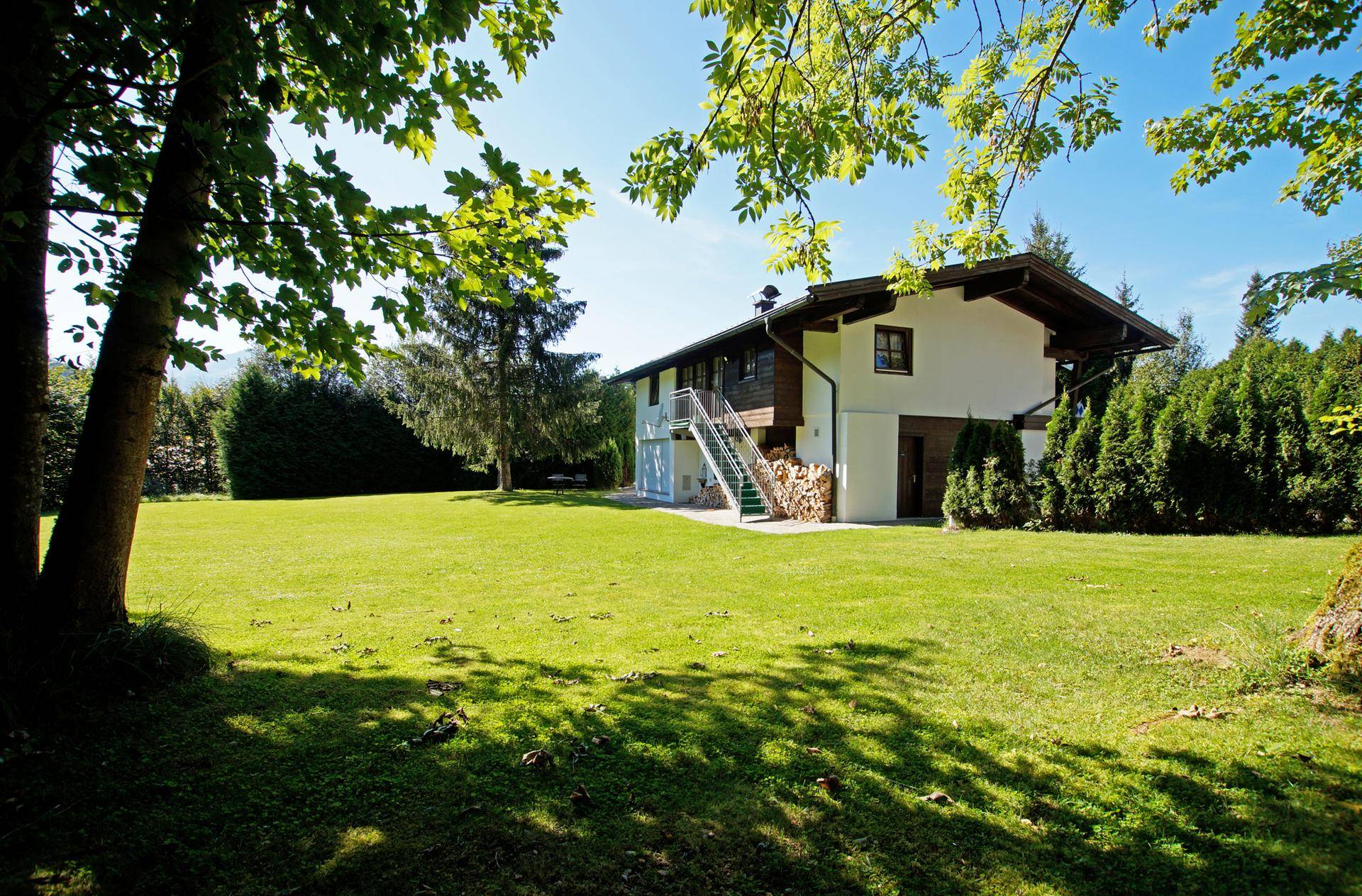 Großer, gepflegter Garten mit weitläufiger Rasenfläche und Blick auf die Rückseite des Hauses.