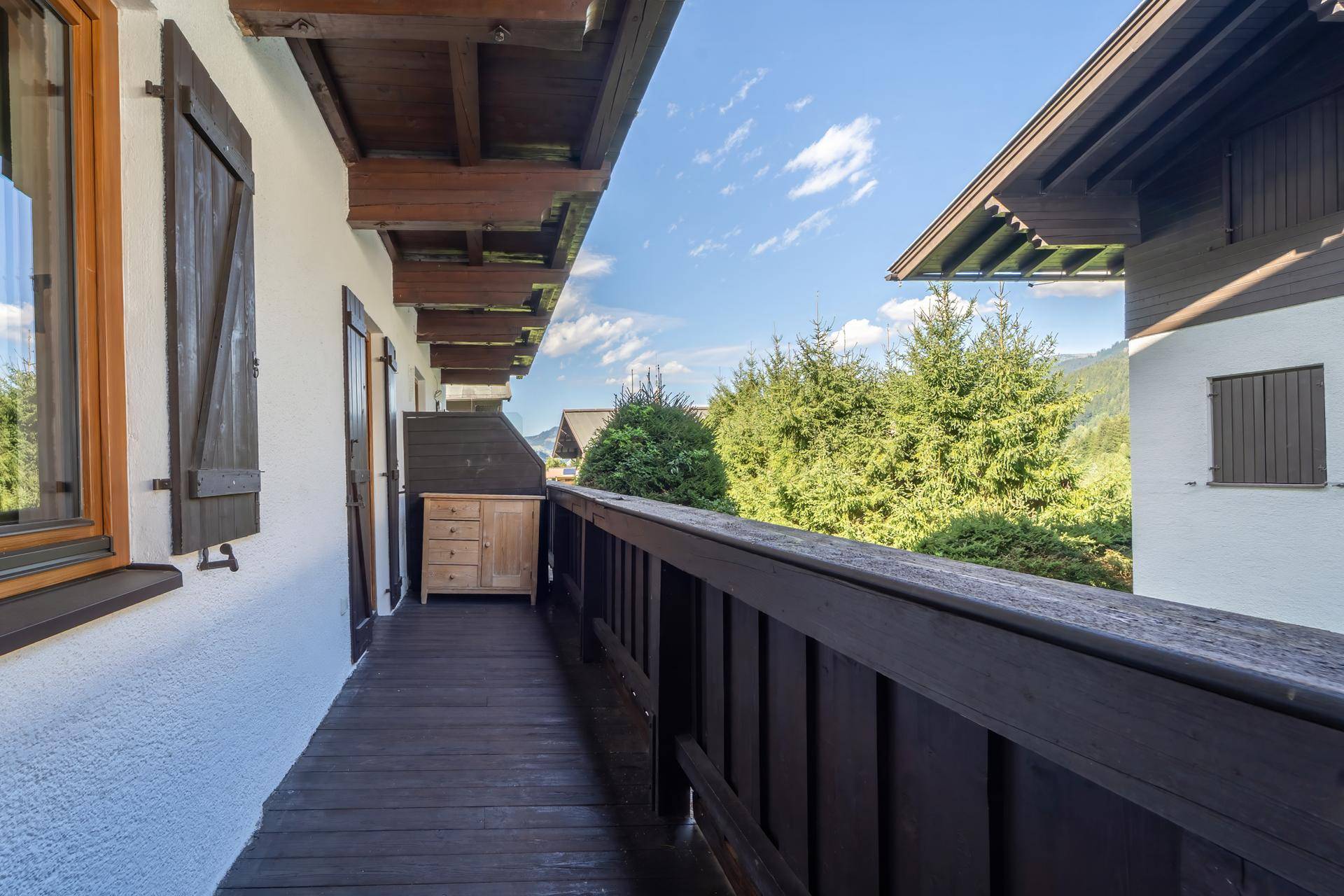 Langer Balkon mit Holzboden, Geländer und Blick auf die umliegende Berglandschaft.