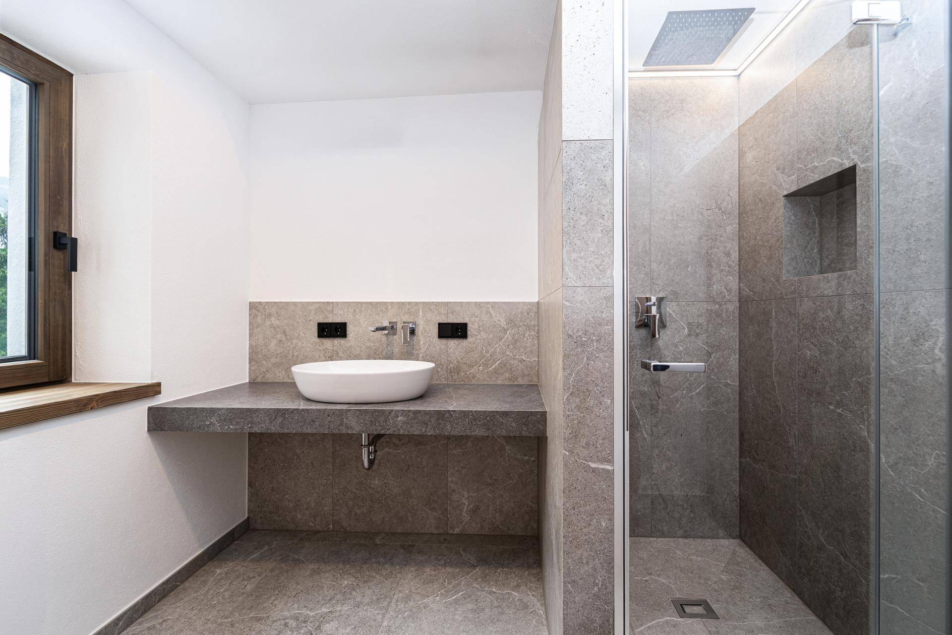 Modernes Badezimmer mit großformatigen Fliesen, begehbarer Dusche und Einzelwaschbecken.