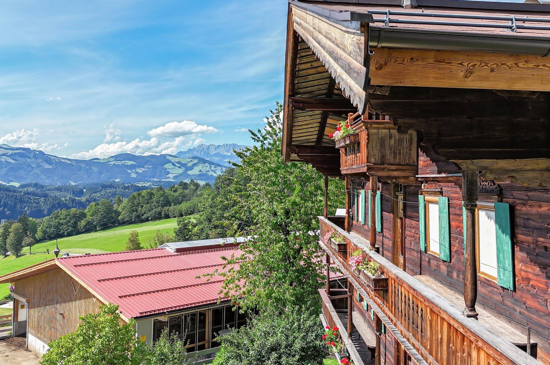 Seitenansicht eines traditionellen Holzhauses mit Balkonen und weitem Blick auf die Berglandschaft.