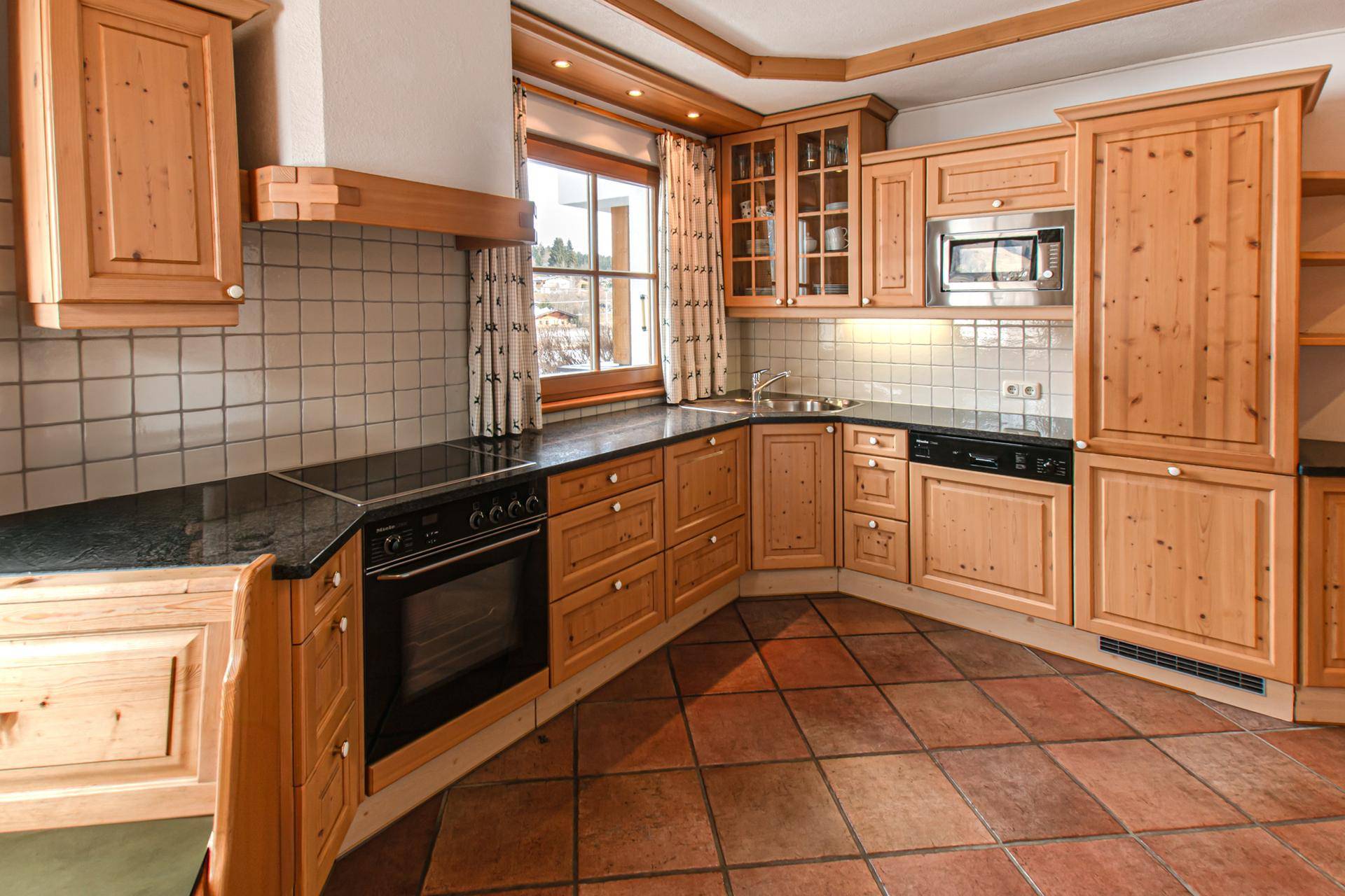 Gemütliche Holzküche im Landhausstil mit Terrakottafliesen und integrierten Geräten.