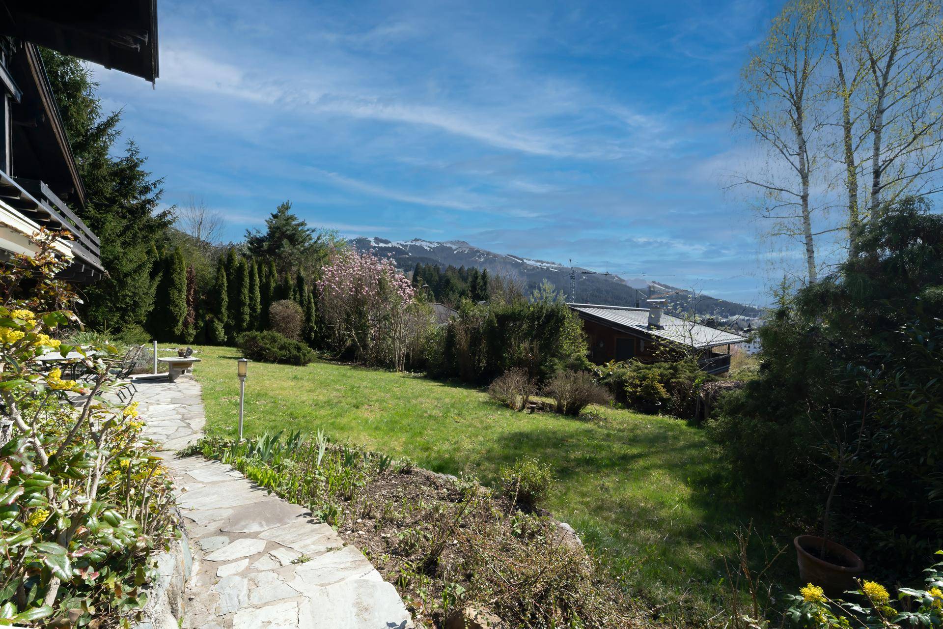 Großer, gepflegter Garten mit Steinweg und weitem Blick auf die umliegende Berglandschaft.
