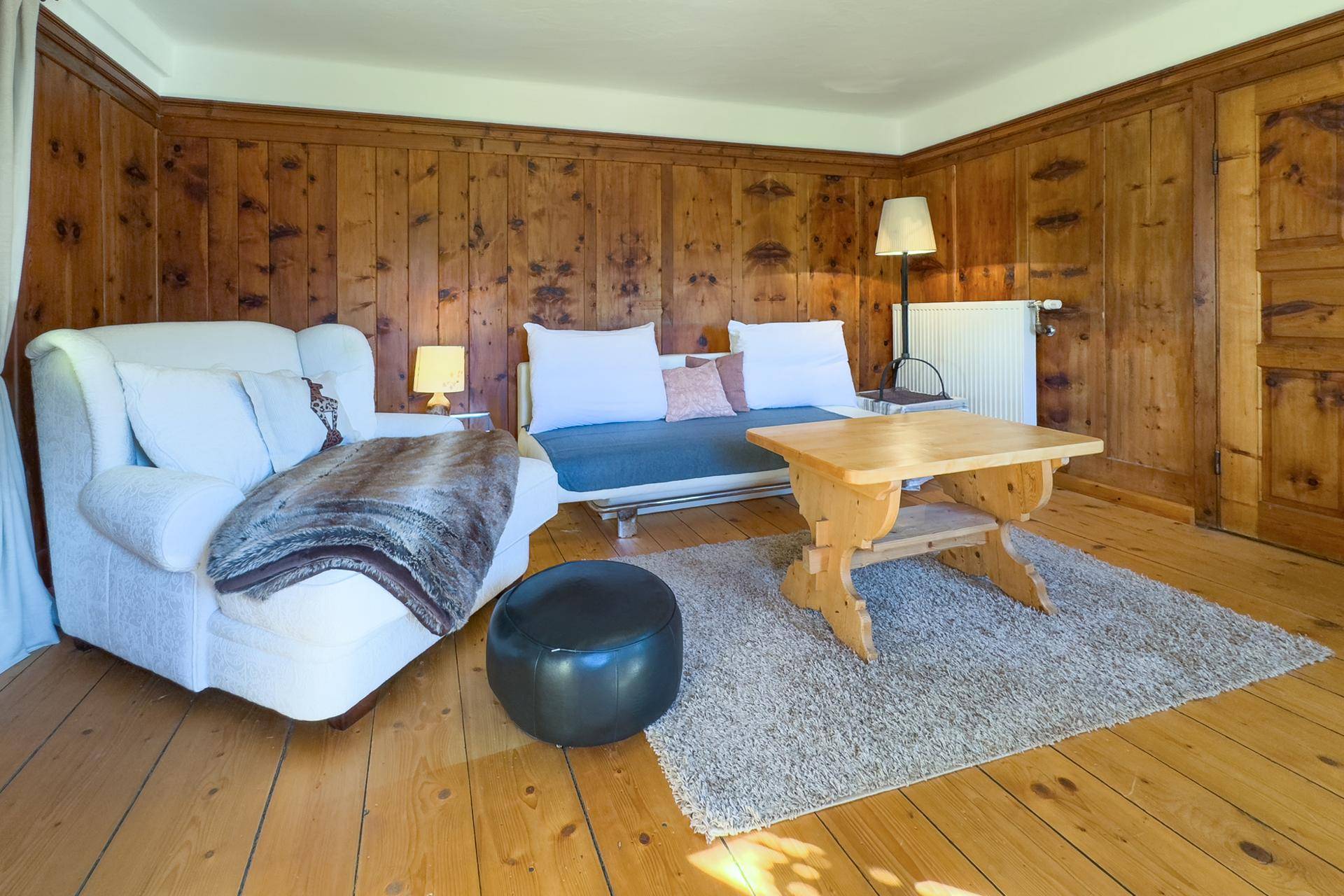 Gemütliches Wohnzimmer im alpinen Stil mit Holztäfelung, bequemen Möbeln und Holzboden.