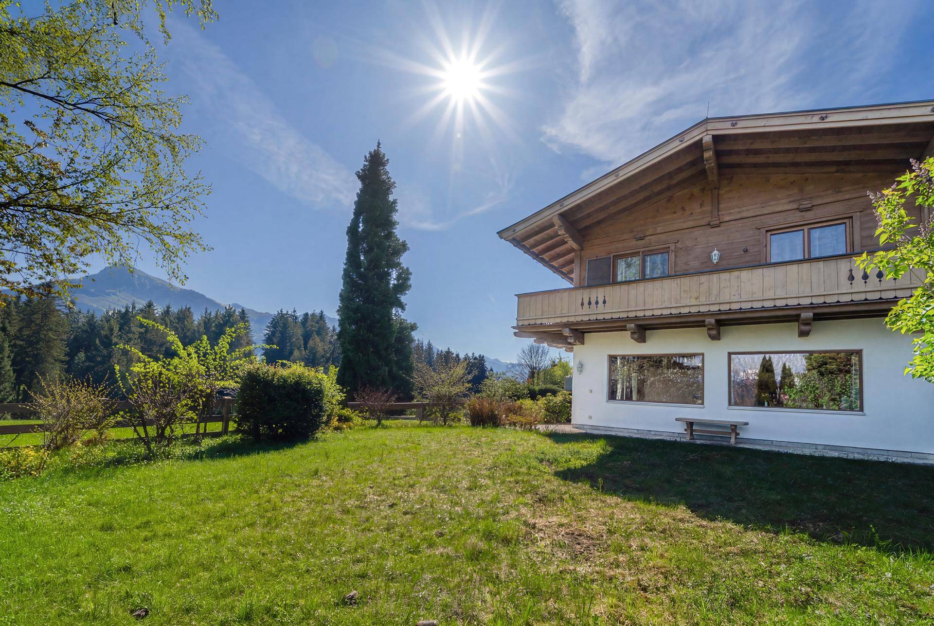 Das traditionelle Holzhaus mit weißer Fassade und großem Garten unter strahlendem Sonnenschein.