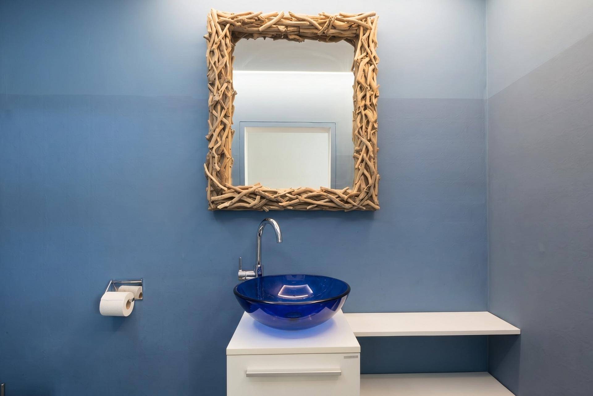 Modernes Gäste-WC mit blauen Wänden, einzigartigem Holzspiegel und blauem Glaswaschbecken.